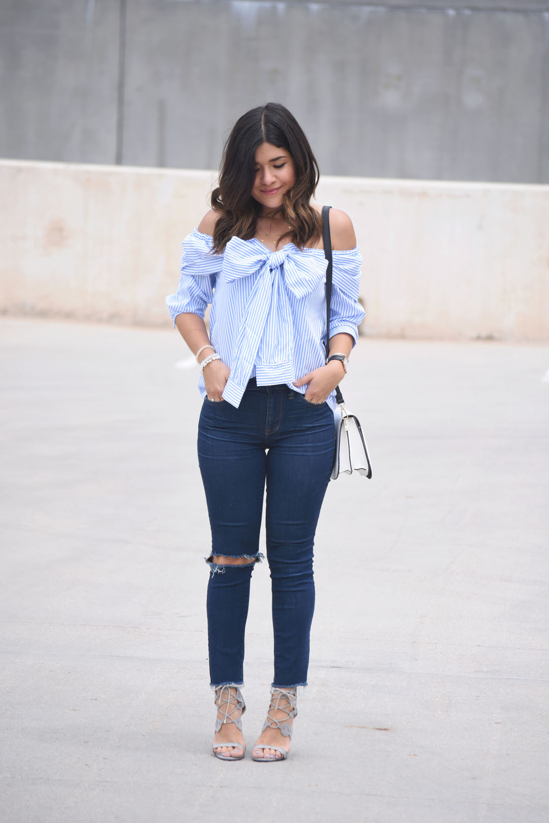 Carolina Hellal of the fashion blog Chic Talk wearing a SheIn tie front off the shoulders blouse, Madewell ripped jeans, and Public Desire grey sandals