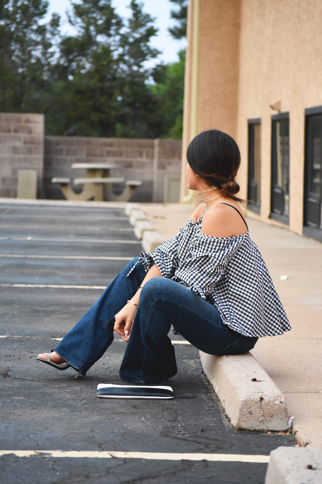 Carolina Hellal of Chic Talk wearing a chicwish gingham off the shoulder top, American Eagle bell bottom jeans, and le motto black and white clutch 