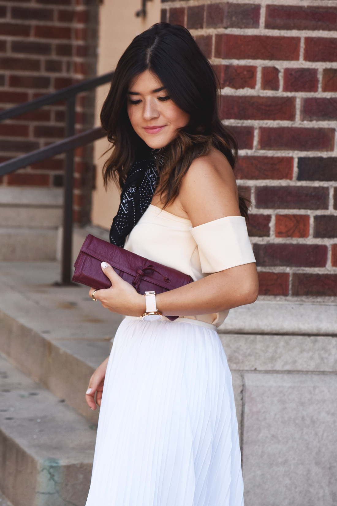 Carolina Hellal of Chic Talk wearing a SheIn off the shoulder top, Kensie pleated skirt, and Prett fast burgundy clutch. 