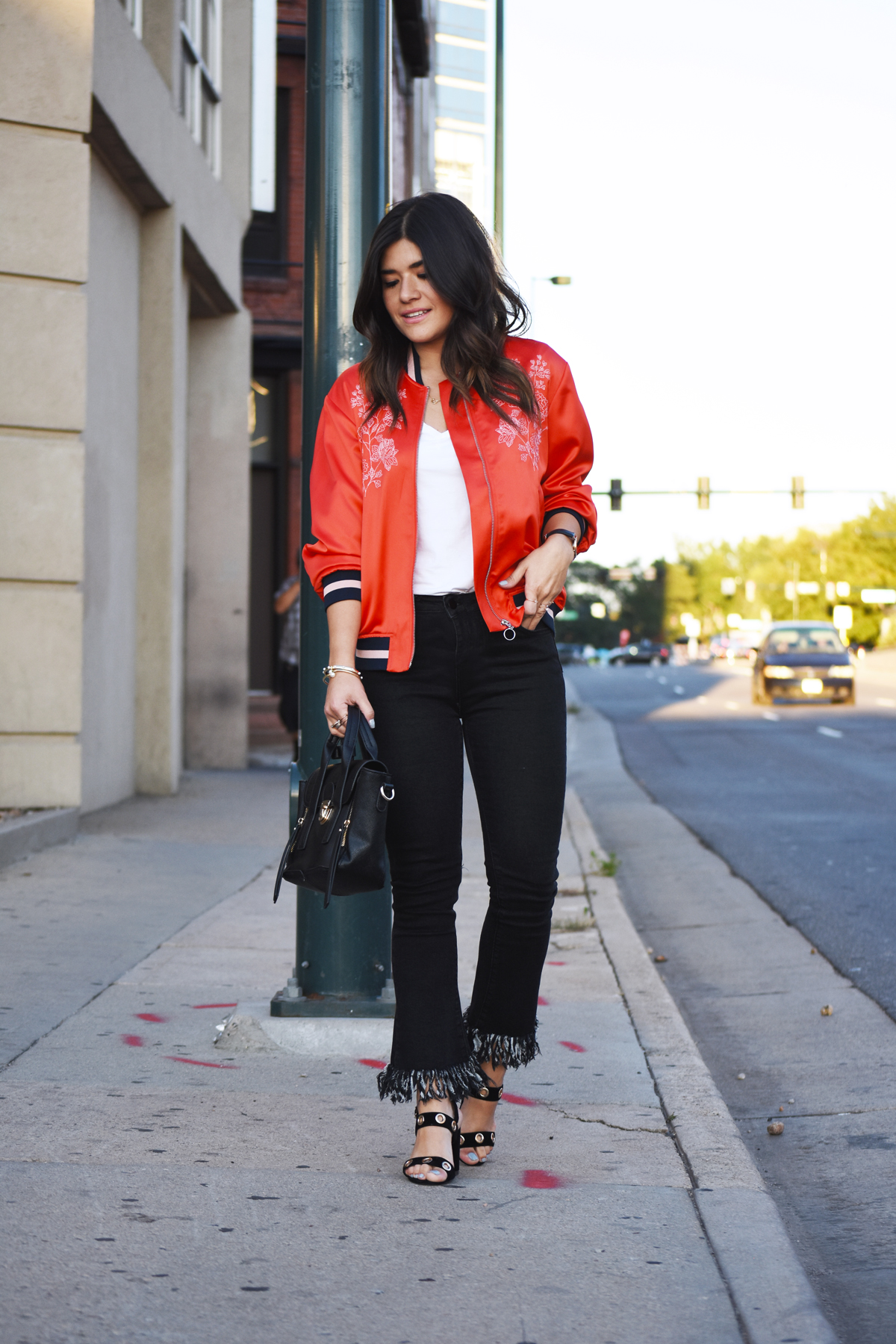 Carolina Hellal of Chic Talk wearing a red H&M Bomber jacket, Dezzal fringed jeans, and Public Desire black sandals