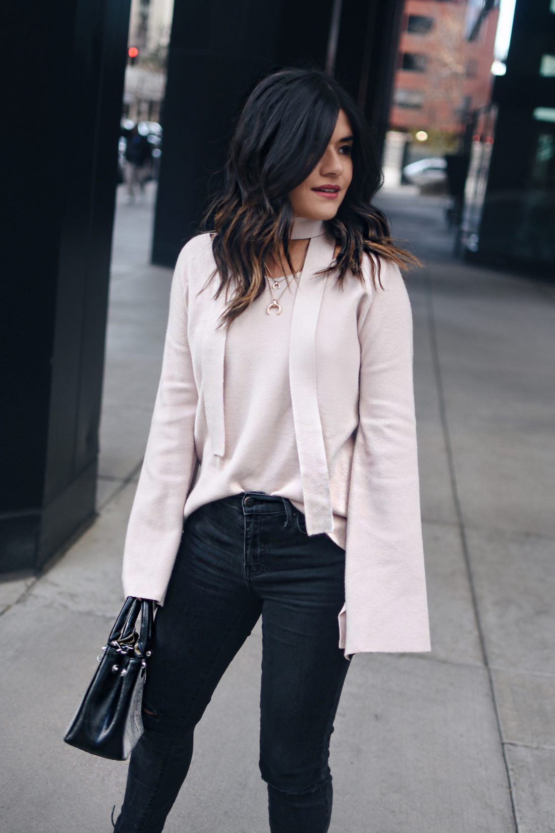 Carolina Hellal of Chic Talk wearing a Chicwish bell sleeve sweater, Madewell ripped jeans, Topshop leather jacket, and Public Desire sandals.