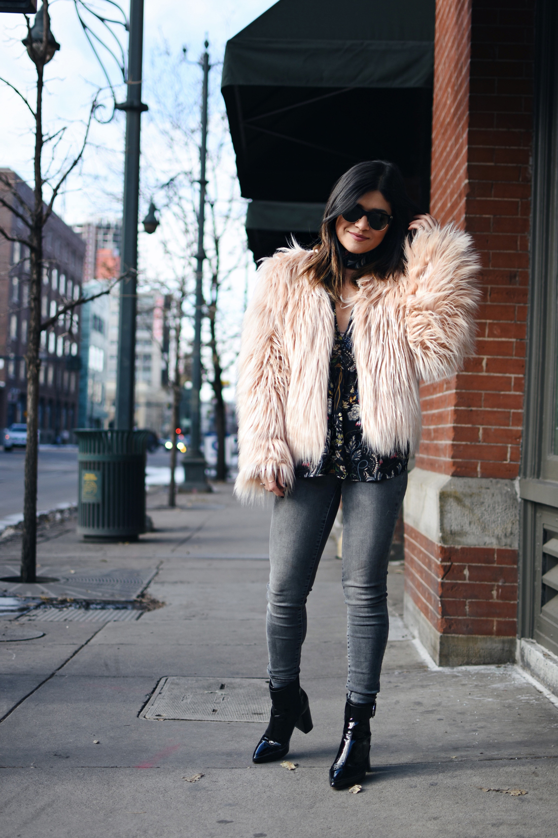 Carolina Hellal of Chic Talk wearing a floral top, furry pink coat, Madewell jeans, and h&m black booties