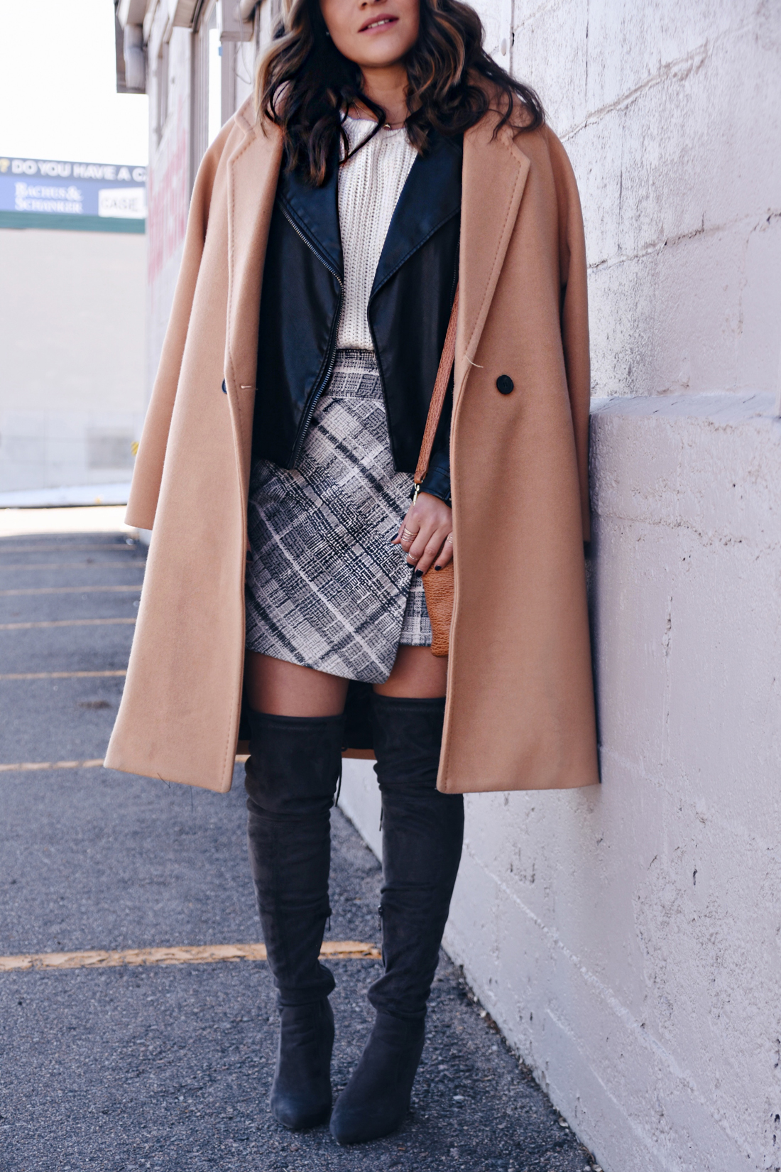 Carolina Hellal of Chic Talk wearing a Chicwish camel coat, plaid skirt, Topshop faux leather jacket, and Public Desire over the knee boots