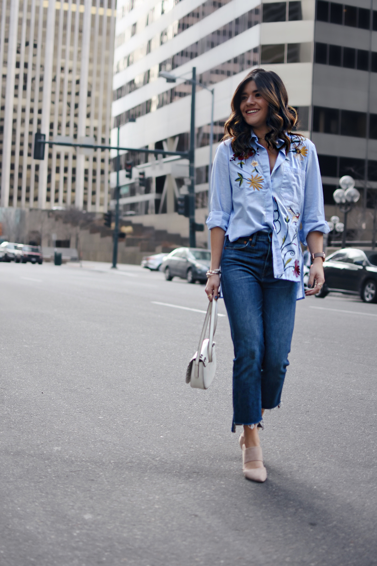 Carolina Hellal of Chic Talk wearing a Chicwish embroidered top, Madewell raw hem jeans, Frye white crossbody bag, and NA-KD fashion nude mules. 