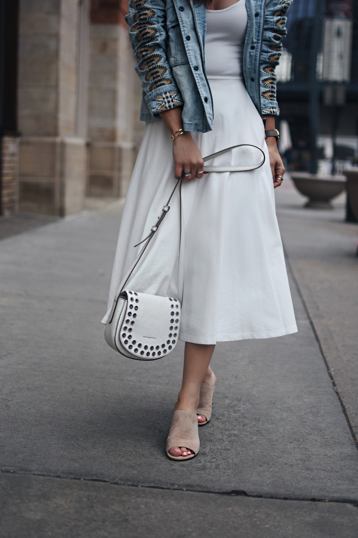 Carolina Hellal of Chic Talk wearing a Free People denim embroidered jacket, The Frye Company white crossbody bag, Donald J Pliner Ellis sandals, and Leith white A line dress via Nordstrom