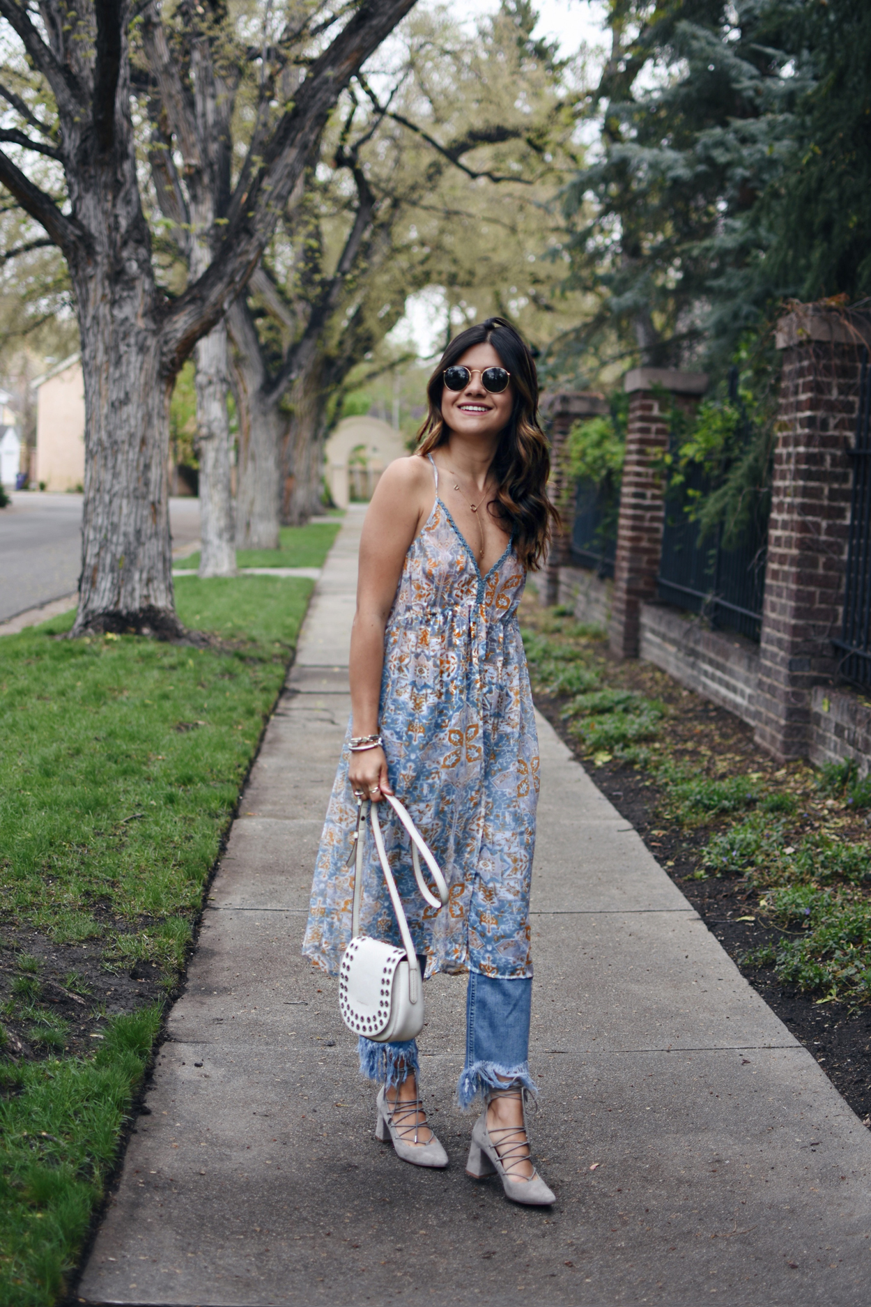 Carolina Hellal of Chic Talk wearing a floral chiffon tunic, fringe jeans, lace up pointy heels and a white crossbody bag