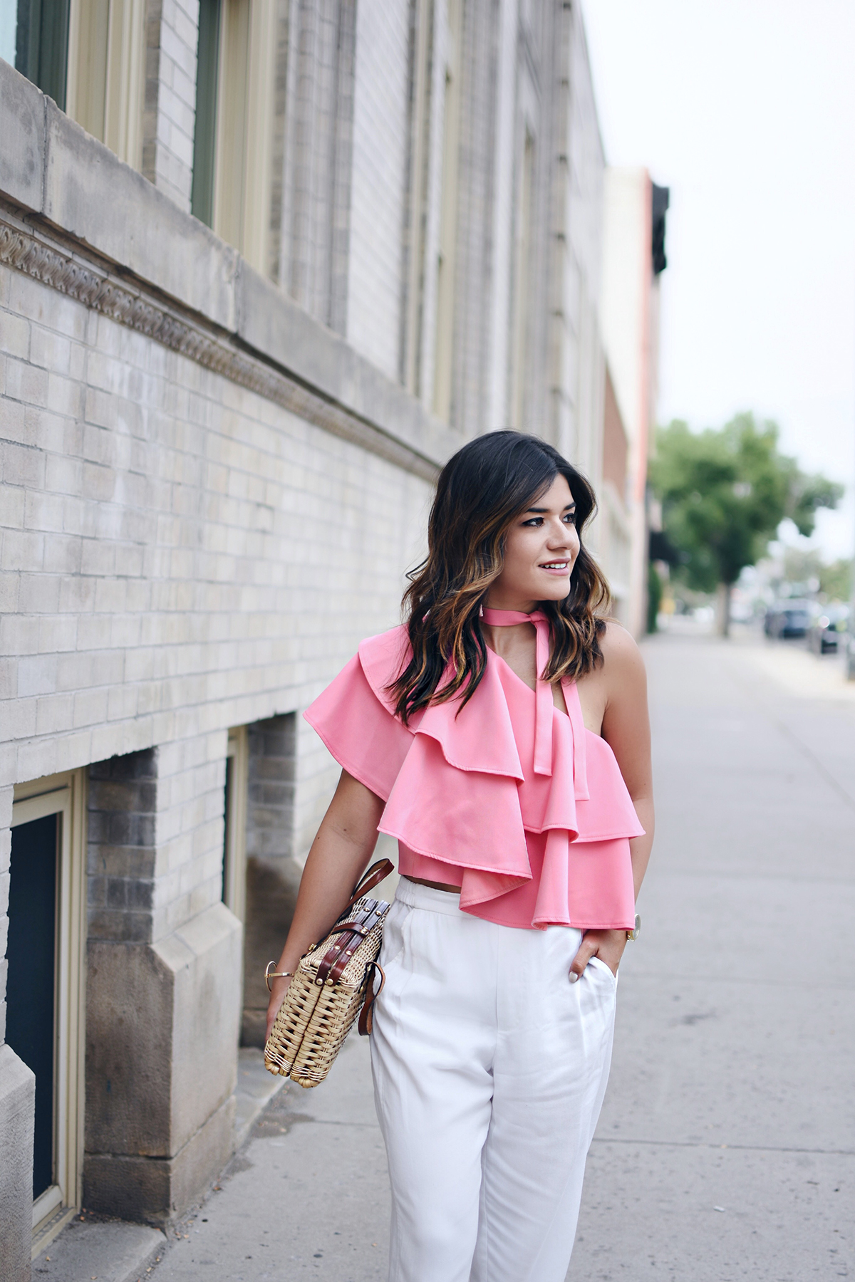 Carolina Hellal of Chic Talk wearing an off the shoulder pink ruffle top with white pants, straw bag and MIA lace up heels 