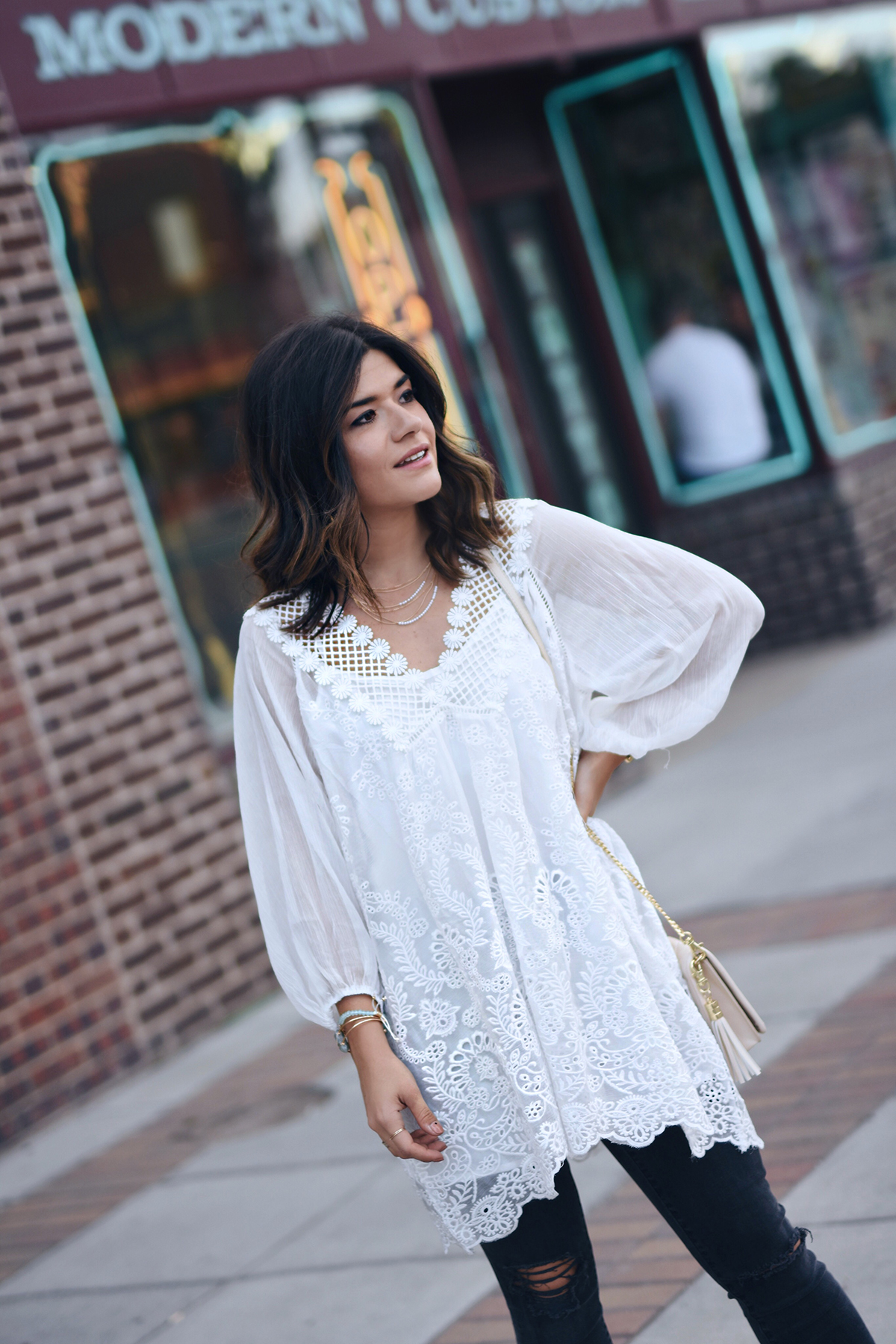 Carolina Hellal of Chic Talk wearing a Chicwish white tunic, Charming Charlie clutch, Madewell jeans and criss cross mules