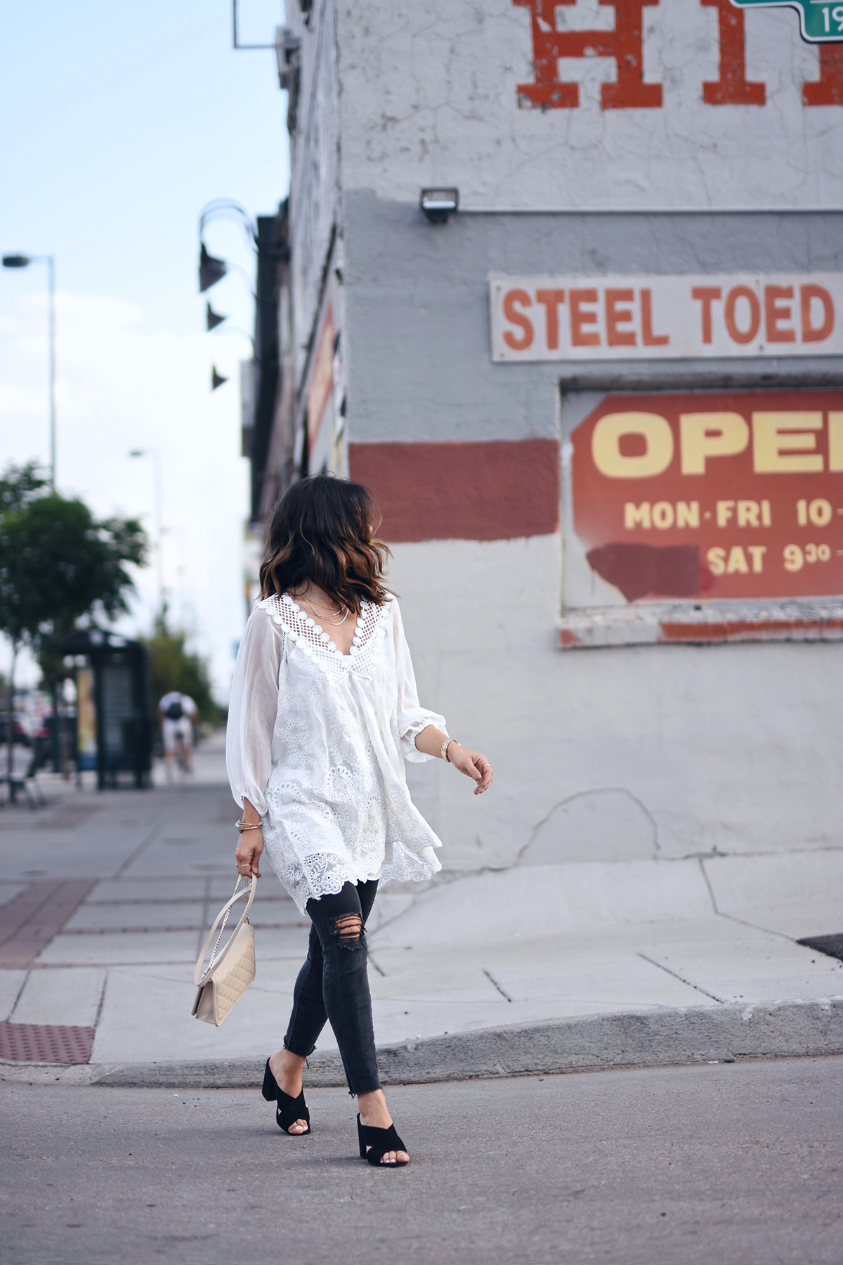 Carolina Hellal of Chic Talk wearing a Chicwish white tunic, Charming Charlie clutch, Madewell jeans and criss cross mules