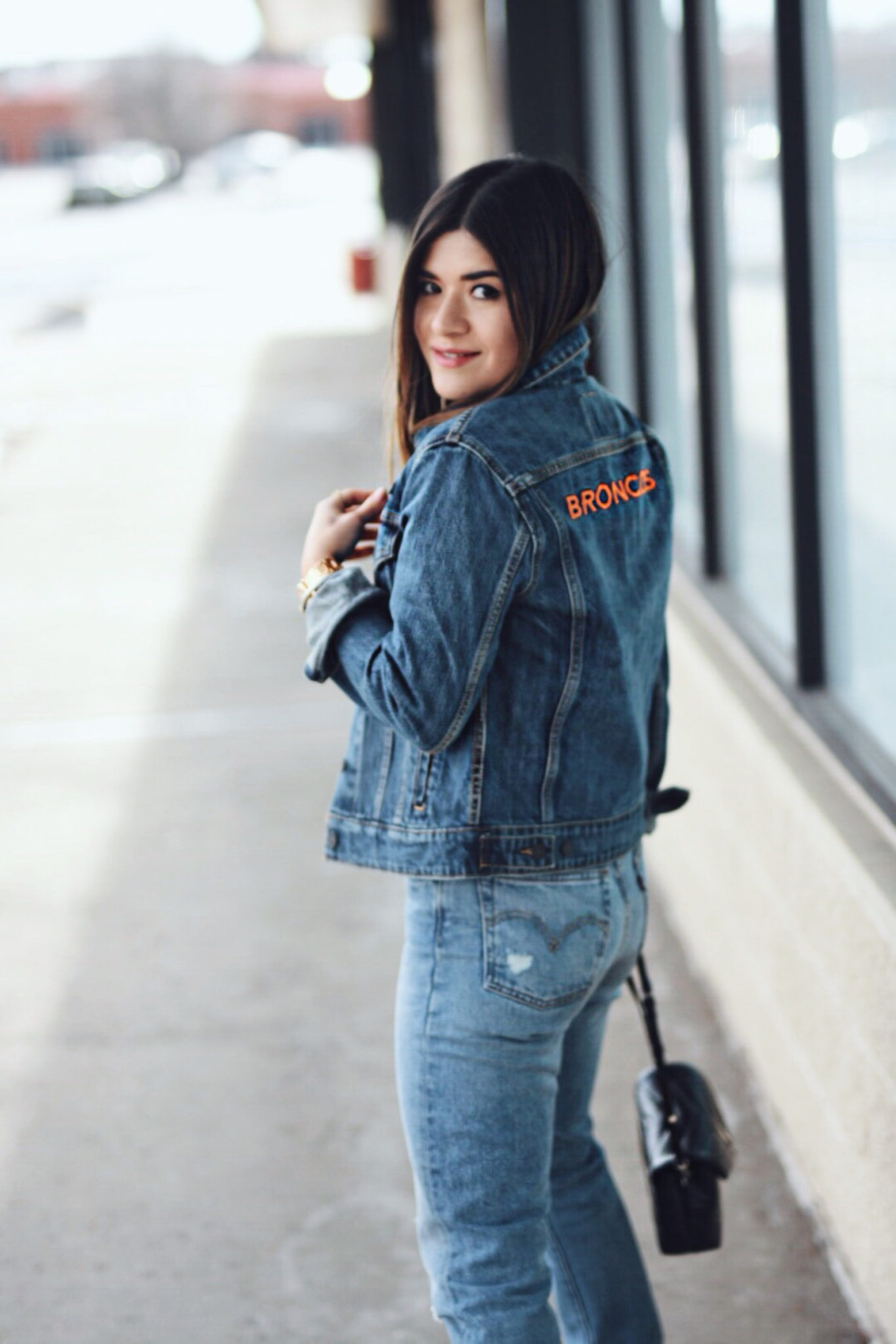 Carolina Hellal of Chic Talk wearing a Levi's Denver Broncos Jacket, Levi's 501 jeans, YSL crossbody bag and Public Desire boots