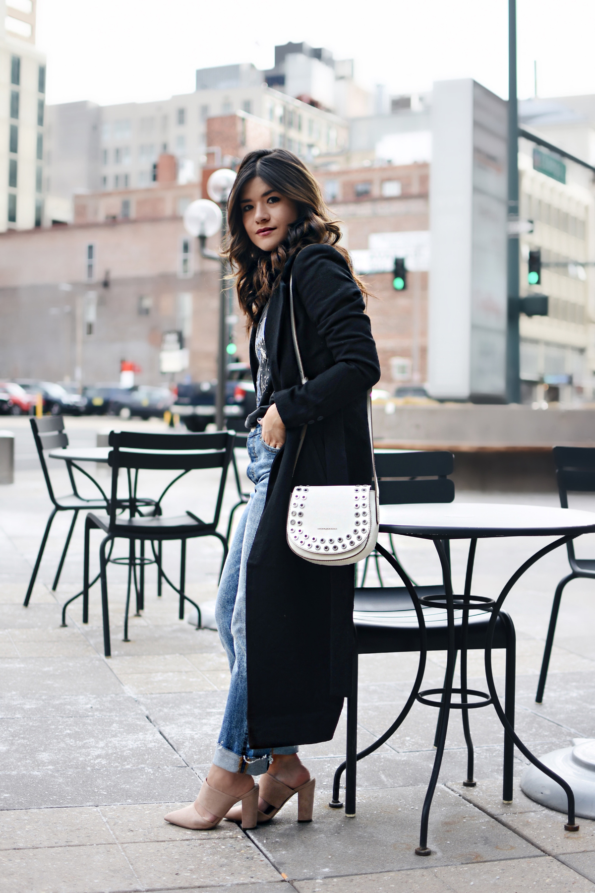 Carolina Hellal of Chic Talk wearing an H&M graphic t-shirt, H&m girlfriend jeans, Frey company white crossbody bag, and NA-KD fashion mules and black coat. - HOW TO STYLE GIRLFRIEND JEANS by popular Denver fashion blogger Chic Talk