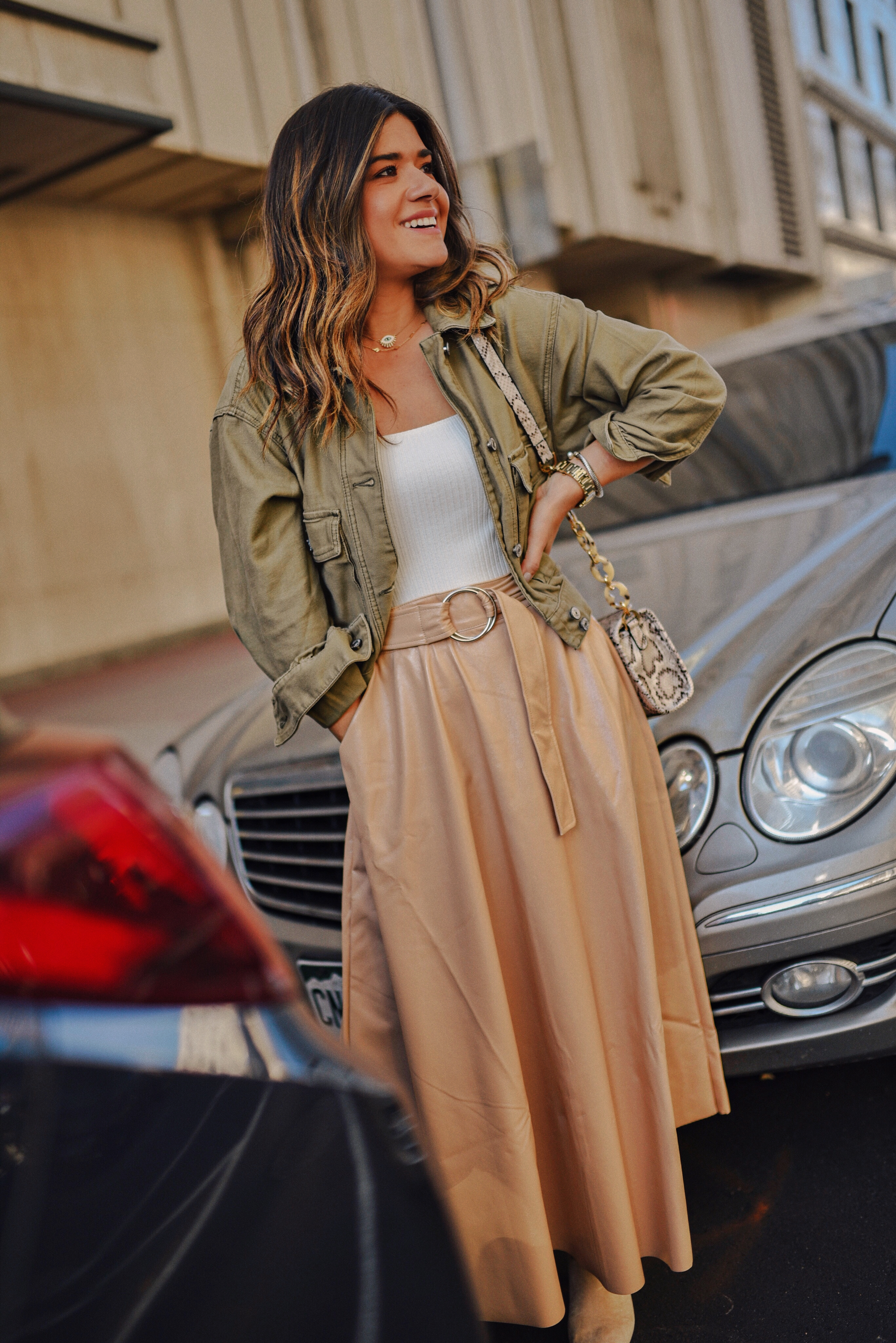 Carolina Hellal of Chic Talk wearing a Topshop white bodysuit, beige faux leather midi skirt, Abercrombie jacket, and Vici suede beige ankle boots. 