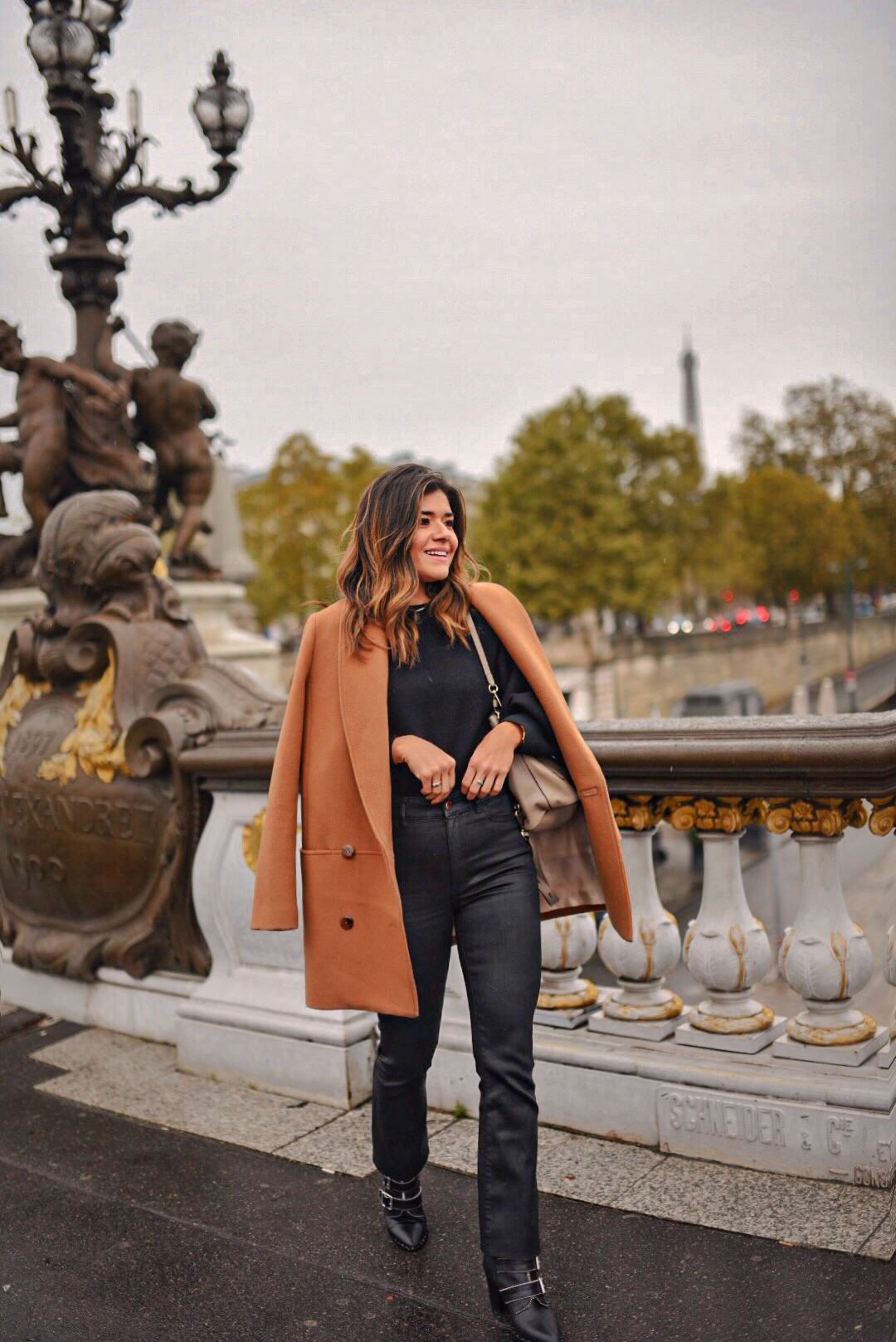 Carolina Hellal of Chic Talk in Paris at the Pont Alexander III wearing a Sezane camel coat