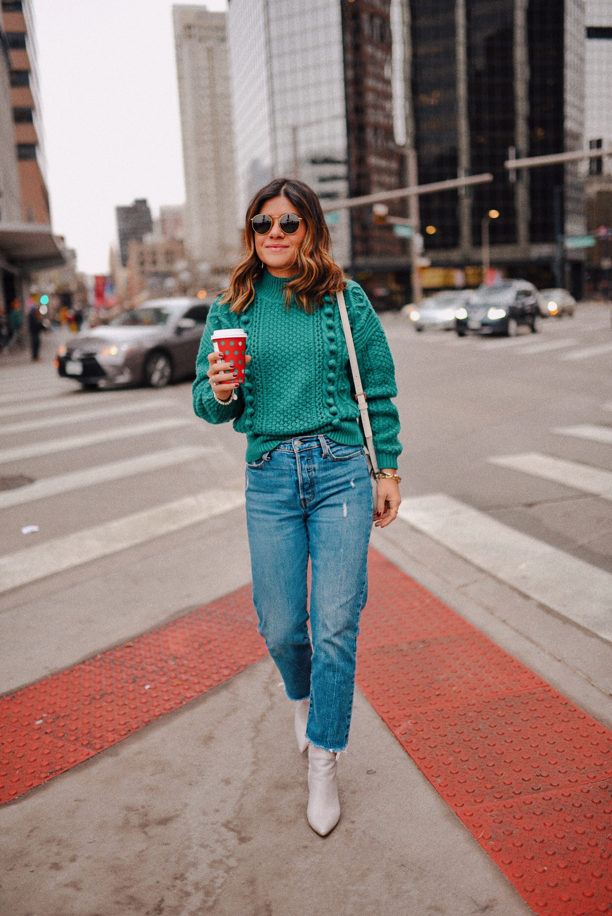 Carolina Hellal of Chic Talk wearing a Sezane green knit sweater, Levi's wedgie jeans, Marc Fisher gray ankle boots and Kate Spade white bag. 