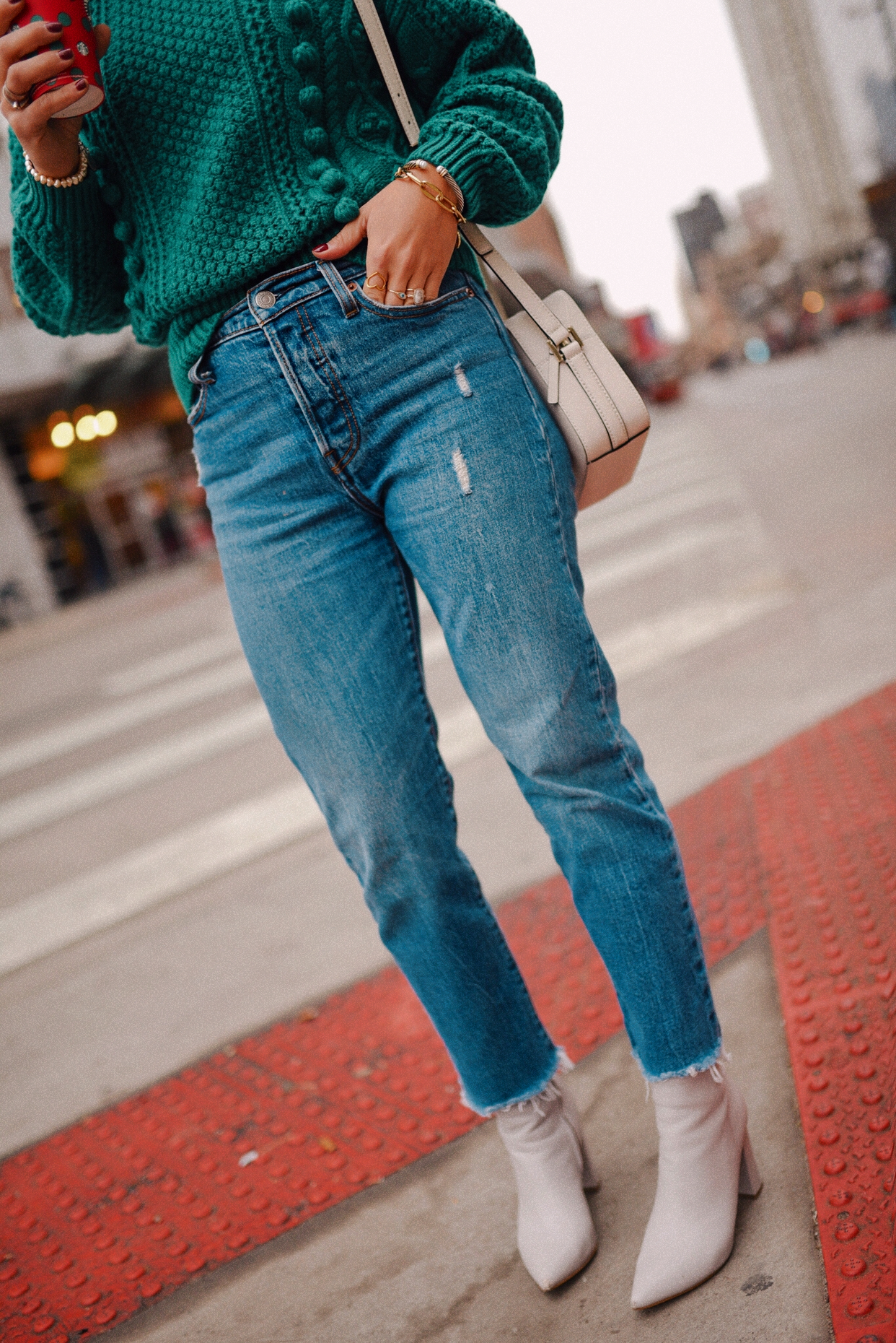 Carolina Hellal of Chic Talk wearing a Sezane green knit sweater, Levi's wedgie jeans, Marc Fisher gray ankle boots and Kate Spade white bag. 