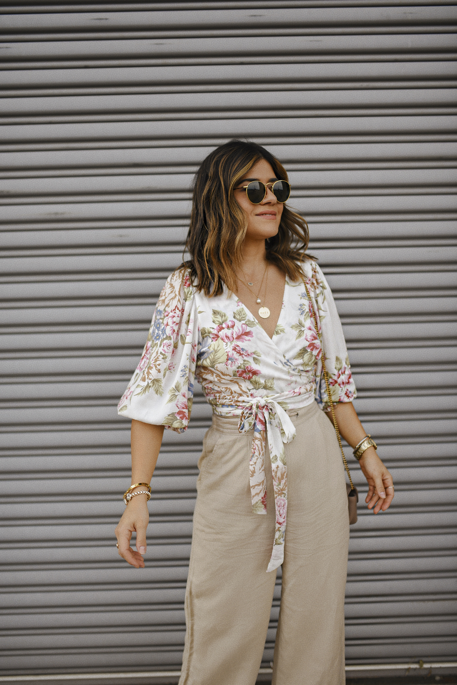 Carolina Hellal of Chic Talk wearing a floral wrap top via Verishop, Linen pants via Target, Rayban rounded sunglasses and a Gucci crossbody bag
