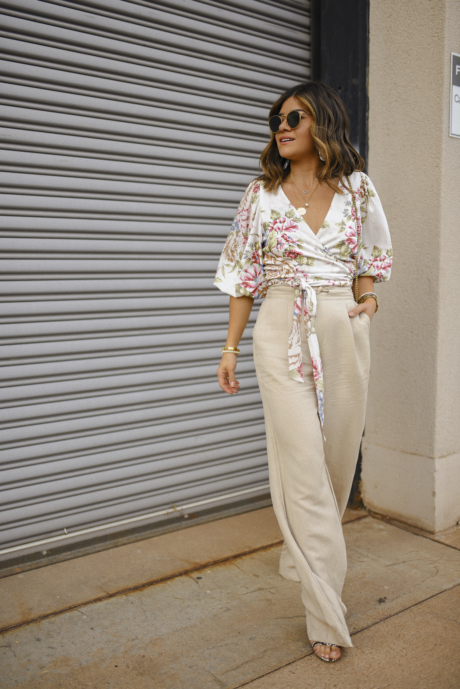 Carolina Hellal of Chic Talk wearing a floral wrap top via Verishop, Linen pants via Target, Rayban rounded sunglasses and a Gucci crossbody bag