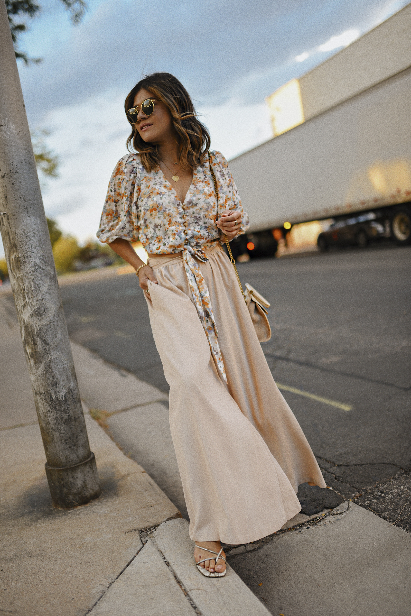 Carolina Hellal of Chic Talk wearing a Chicwish Floral front tie top, nude wide leg pants, Rayban sunglasses, Urban Outfitters sandals and Nat & Nin beige crosssbody bag.