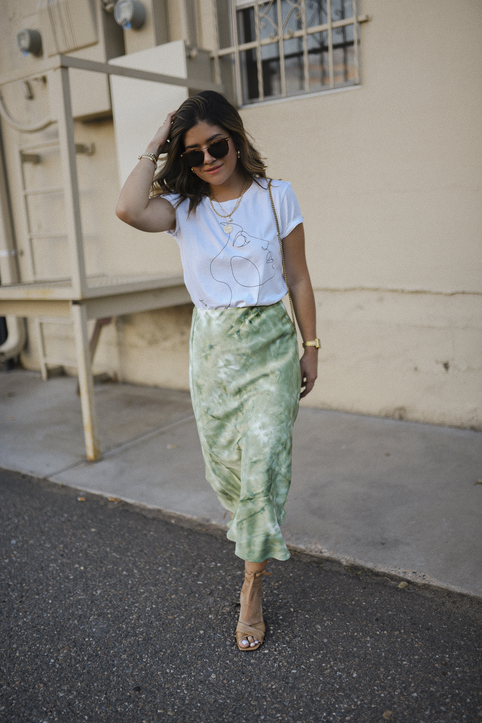 Carolina Hellal of Chic Talk wearing a Lucy Paris graphic tee, tie dye midi skirt, marc fisher sandals and Raen sunglasses.