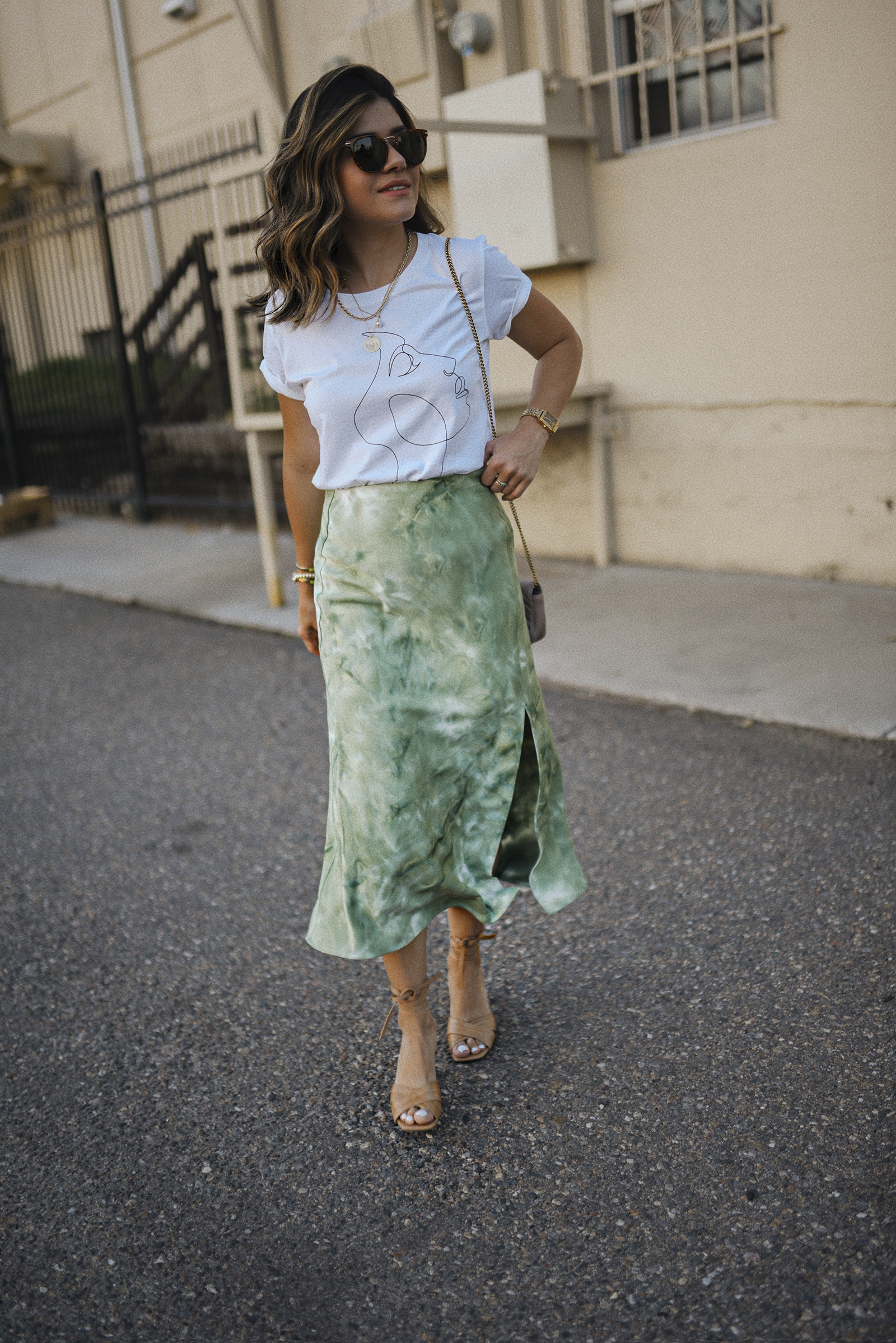 Carolina Hellal of Chic Talk wearing a Lucy Paris graphic tee, tie dye midi skirt, marc fisher sandals and Raen sunglasses. 