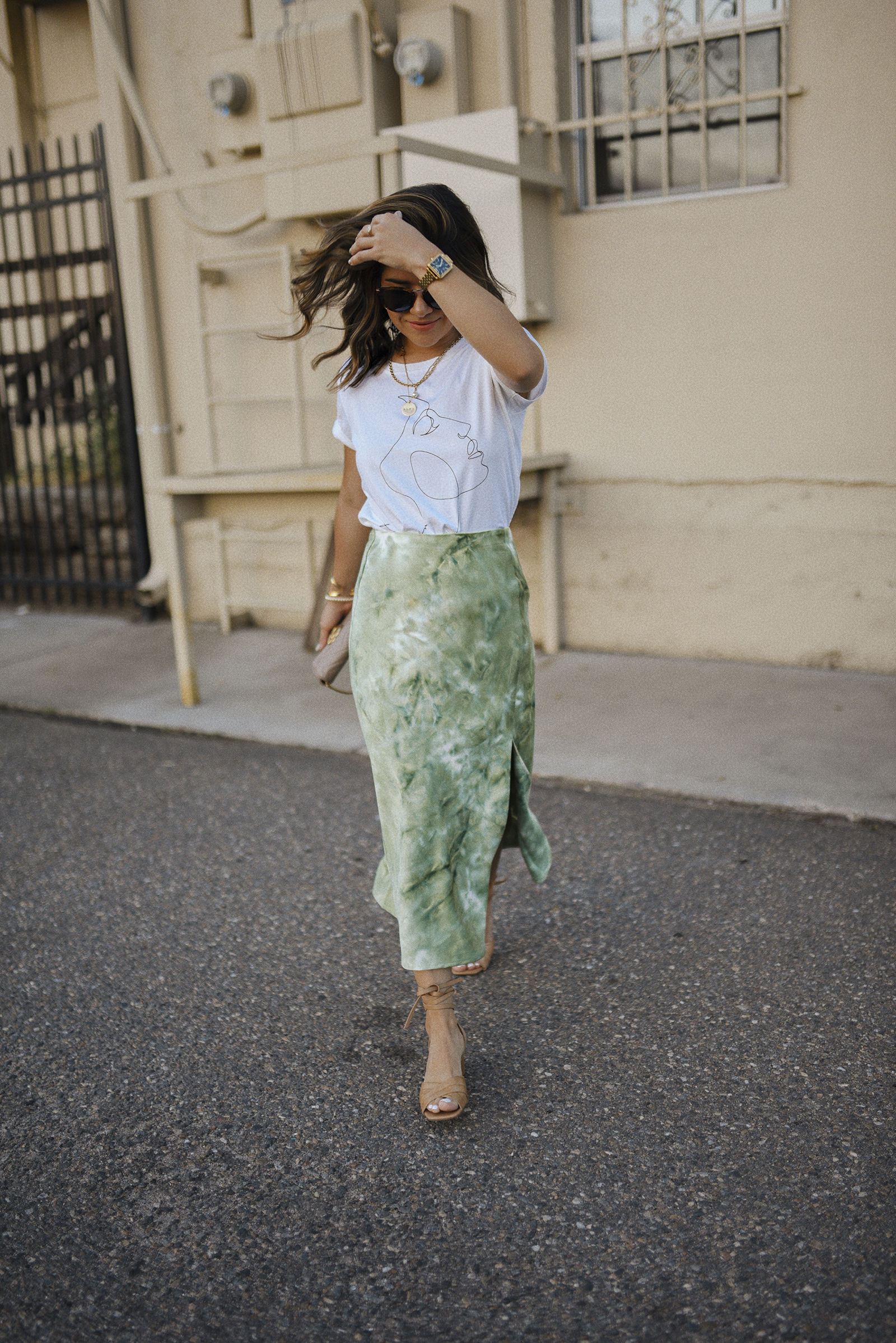 Carolina Hellal of Chic Talk wearing a Lucy Paris graphic tee, tie dye midi skirt, marc fisher sandals and Raen sunglasses.