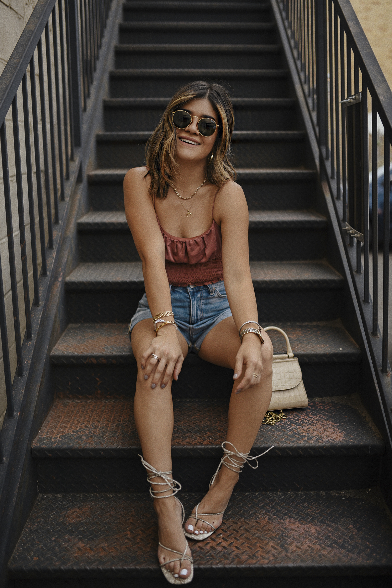Carolina Hellal of Chic Talk wearing a crop top, mom jean shorts and lace up sandals via Urban Outfitters. 