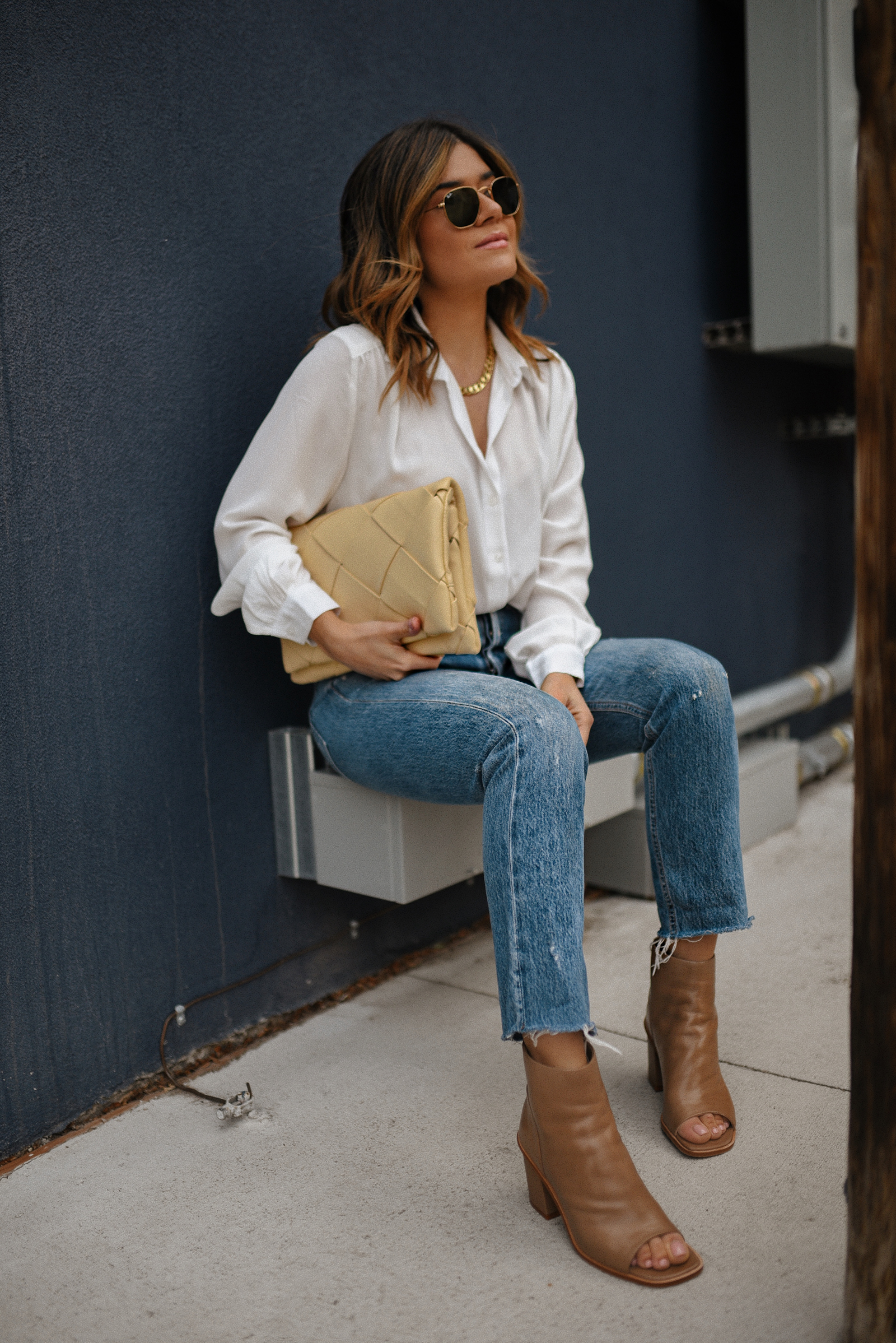 Carolina Hellal of Chic Talk wearing a white button down via H&M, Agolde jeans, Vince Camuto open toe booties, Rayban sunglasses and Topshop yellow clutch. 