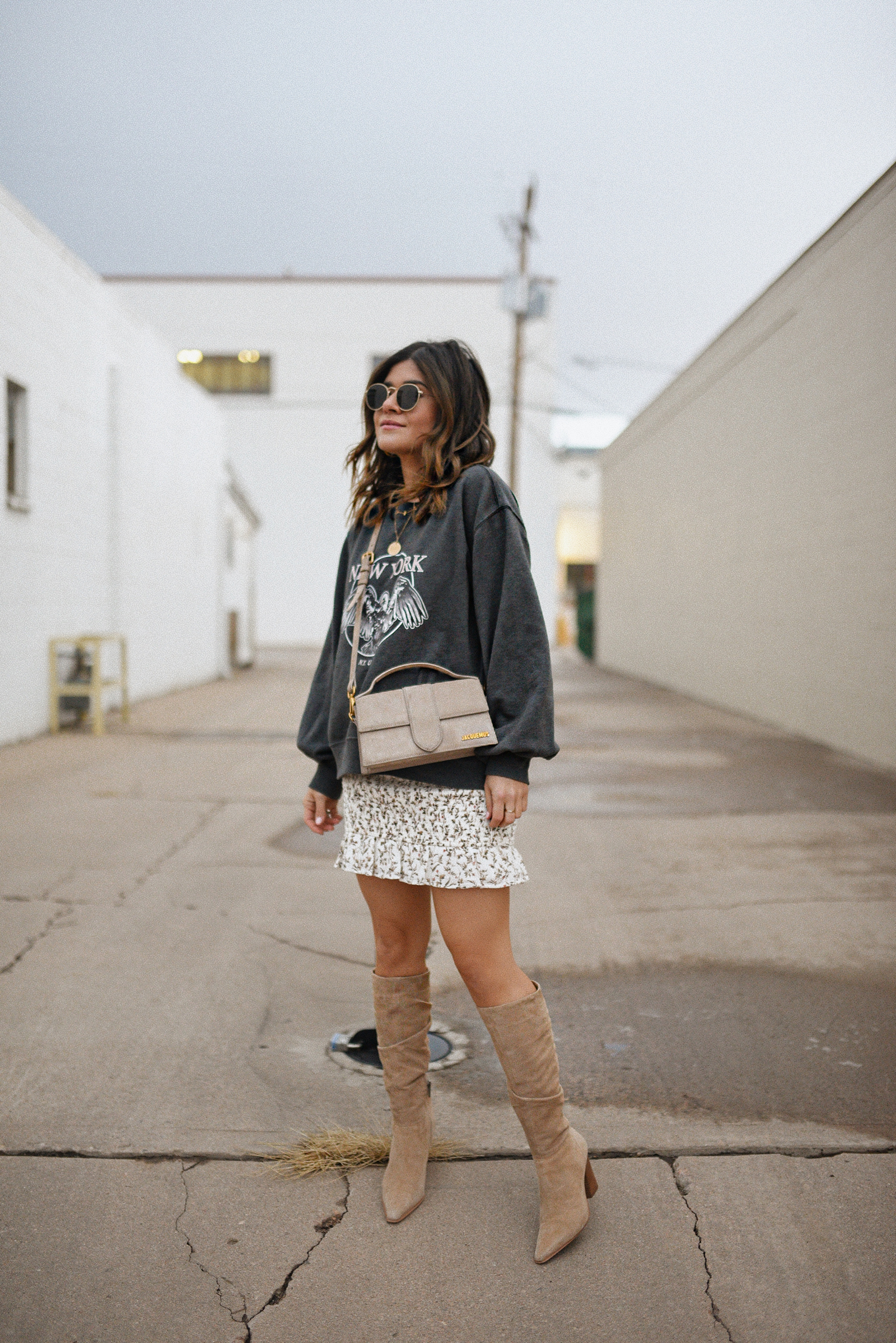 Carolina Hellal of Chic Talk wearing an Abercrombie sweatshirt, mini floral skirt, Vince Camuto suede tall boots and Jacquemus le bambino bag. 