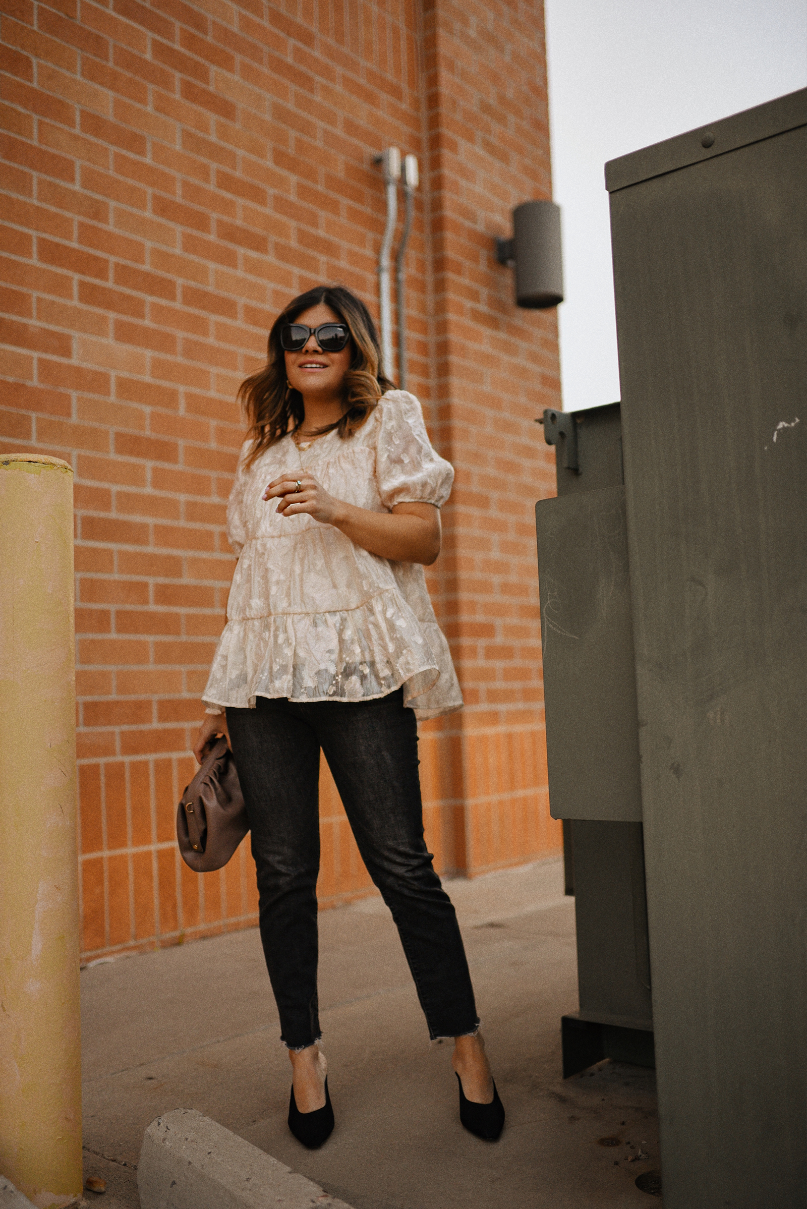 Carolina Hellal of Chic Talk wearing a floral A-line blouse, Levi's grey straight leg jeans, Quay eye cat sunglasses and Pelle moda black mules and Target pouch bag. 