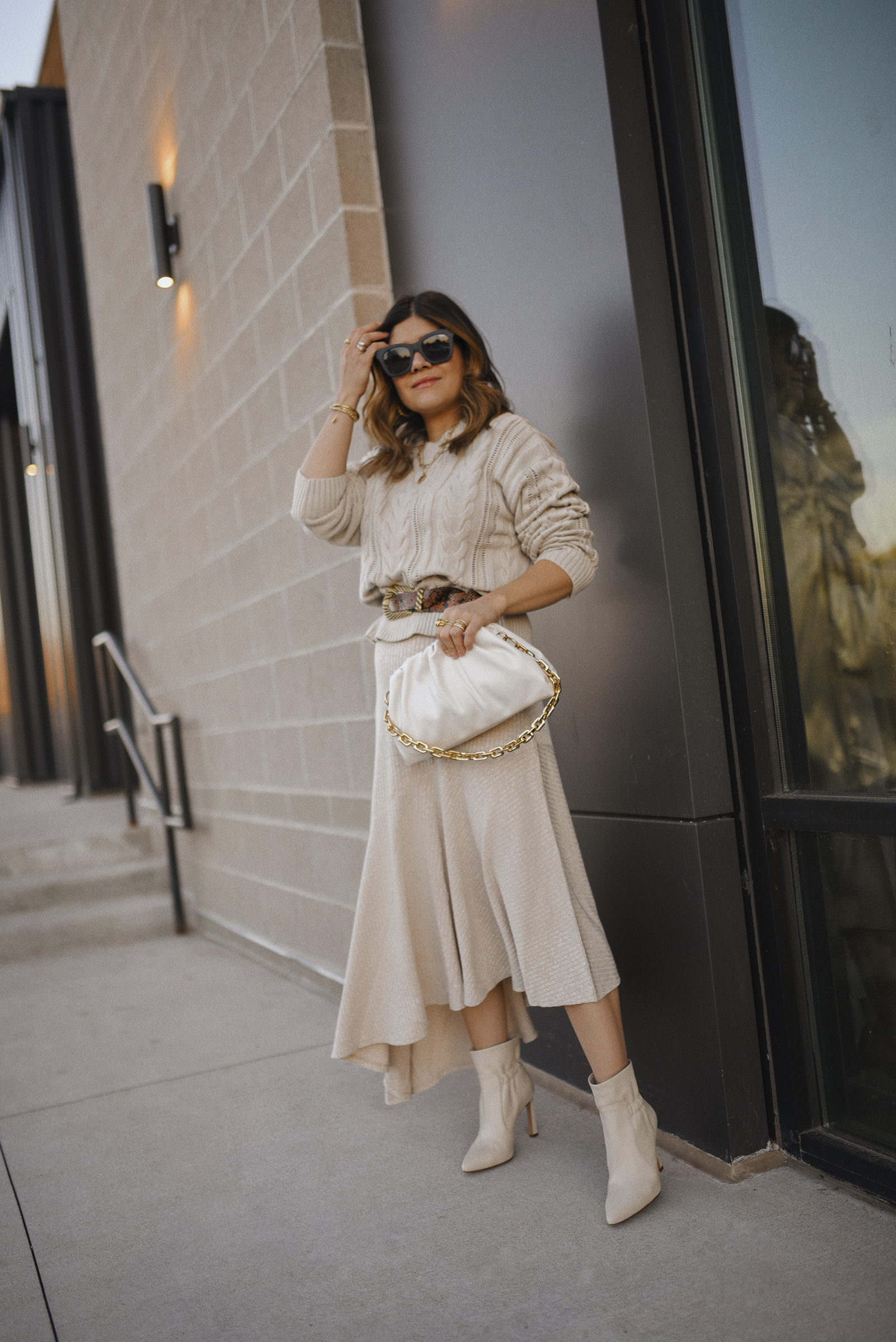 Carolina Hellal of Chic Talk wearing a knit sweater via Walmart, a Free Assembly knit skirt via Walmart, Scoop white bag, QUAY sunglasses and white booties via Vince Camuto.