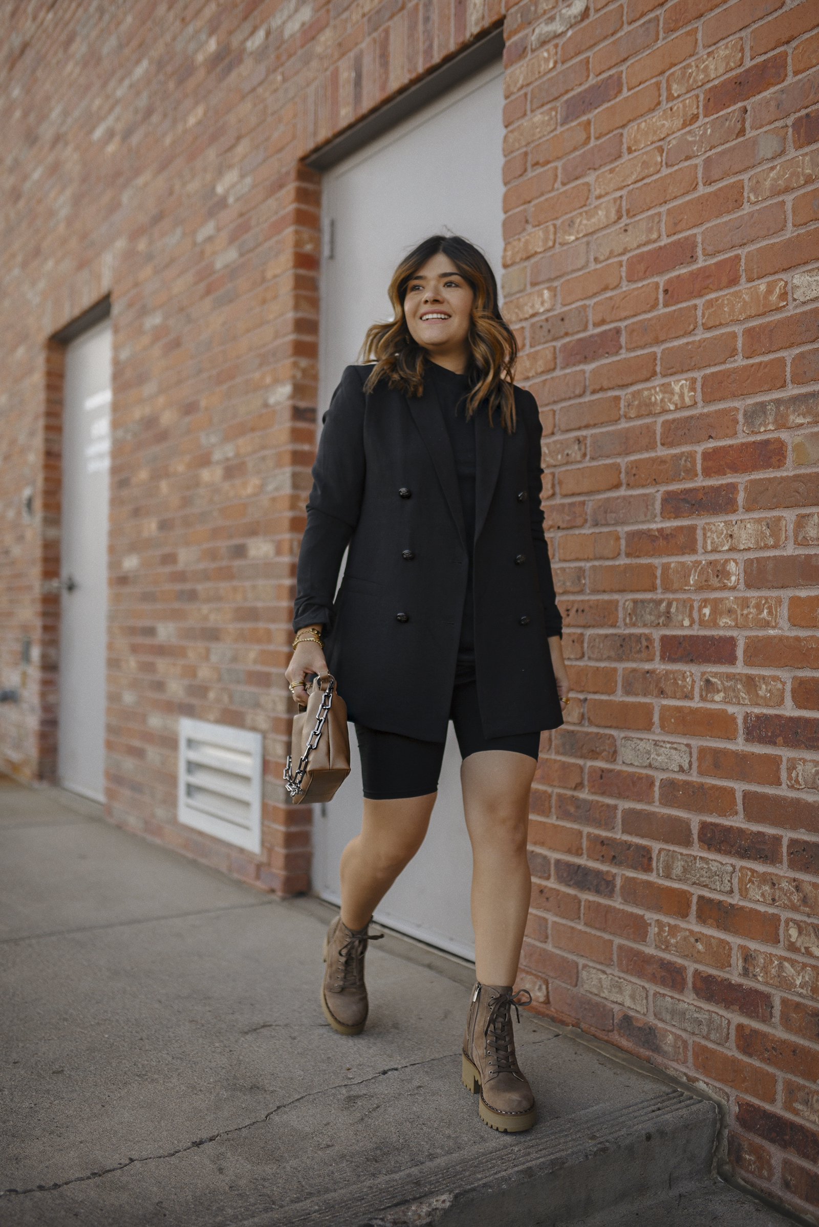 Carolina Hella of Chic Talk wearing a total black look. H&M black blazer and bike shorts, Vince Camuto crossbody bag and chunky boots