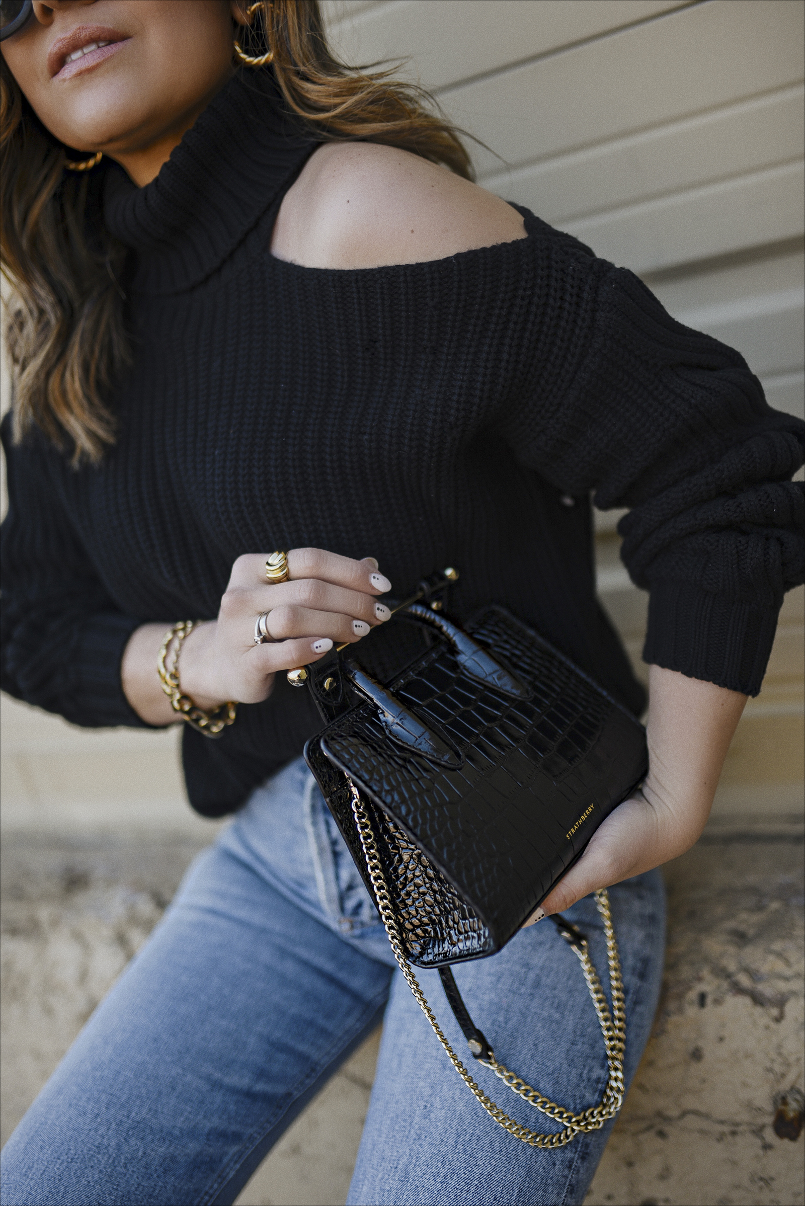 Carolina Hellal of Chic Talk wearing a cutout knit sweater and agolde jeans via Bloomingdales. Black Converse and strathberry bag