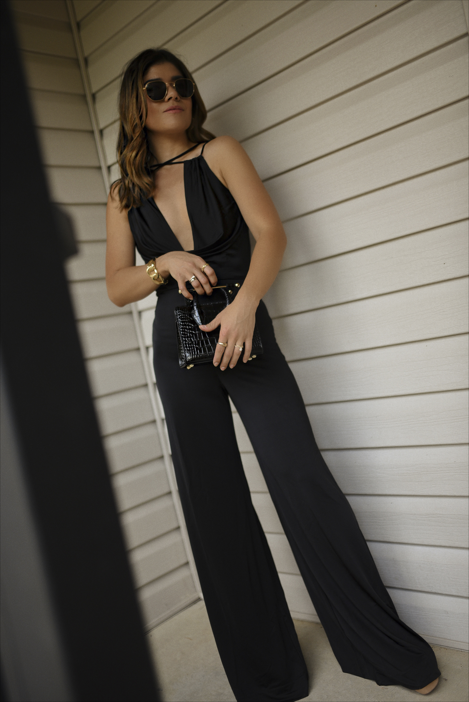Carolina Hellal of Chic Talk wearing a total black look featuring a black jumpsuit via Revolve. A black strathberry bag, Miranda Frye cuff and Rayban sunglasses. 