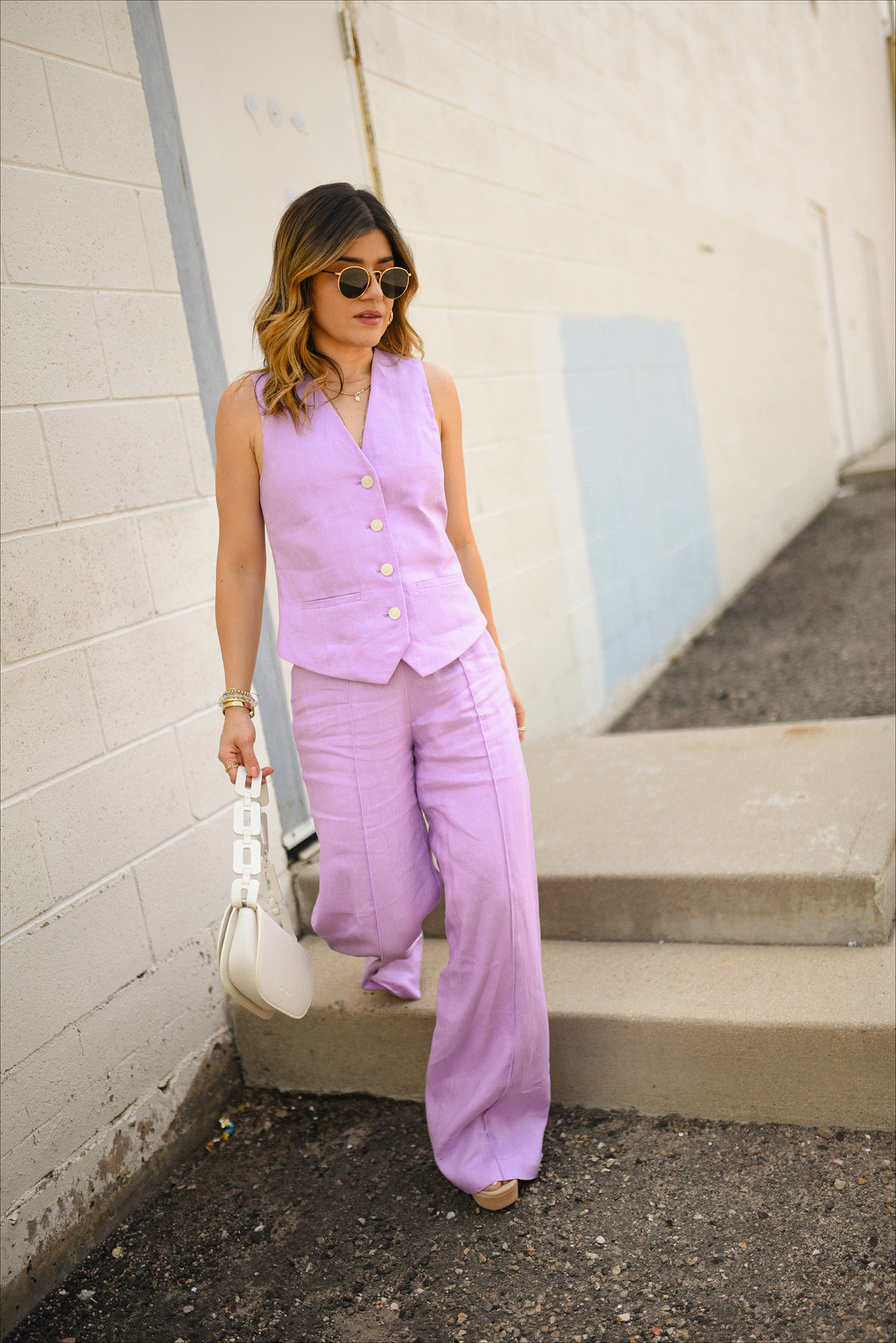 Carolina Hellal of Chic Talk wearing a pink linen set from Mango, Melie Bianco white shoulder bag, Vince Camuto nude sandals, and rounded Rayban sunglasses