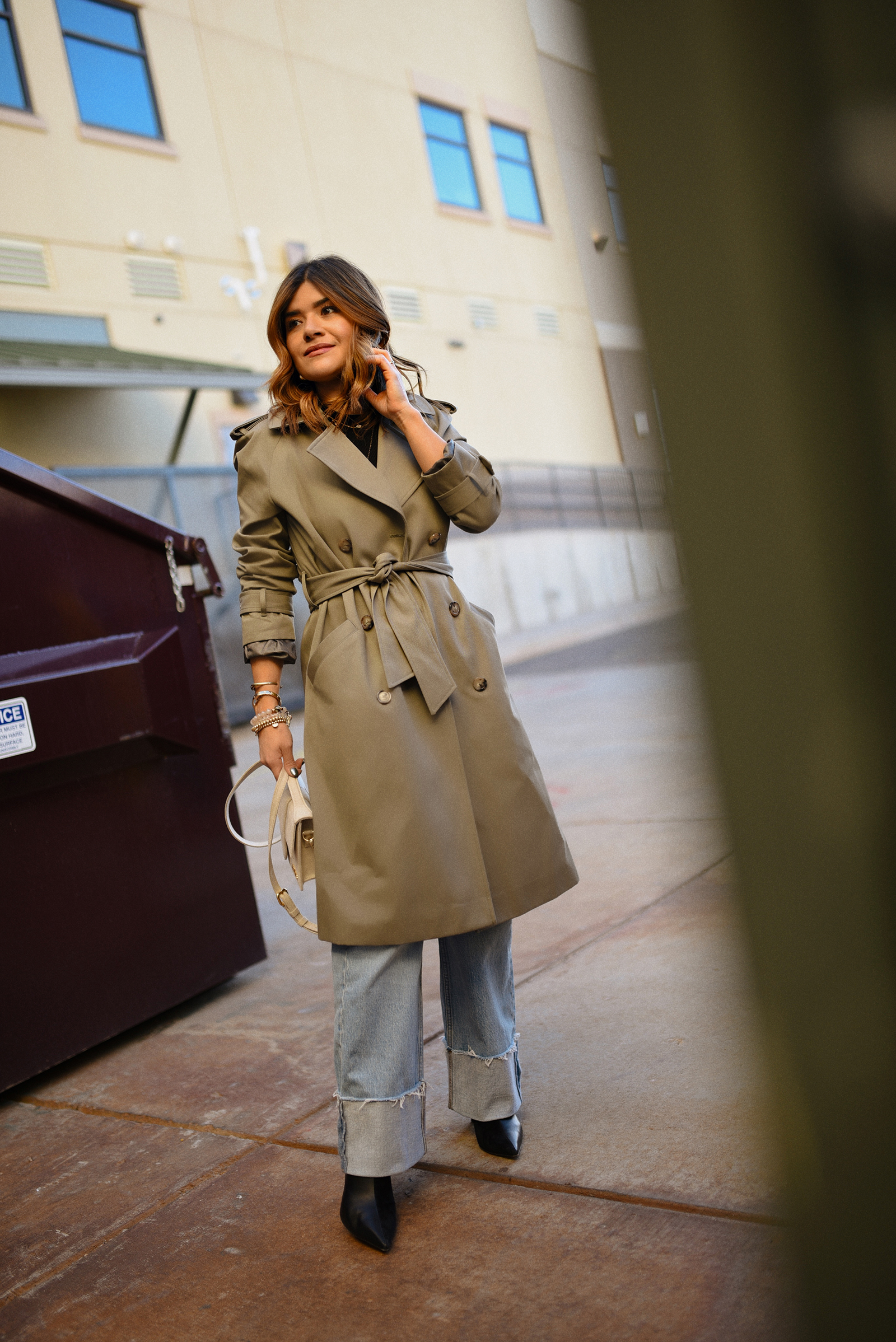Carolina Hellal Of chic Talk wearing a Sézane trench coat, Abercrombie wide leg jeans, Jacquemus La grand Bambino bag and Lafayette black pointy booties. 