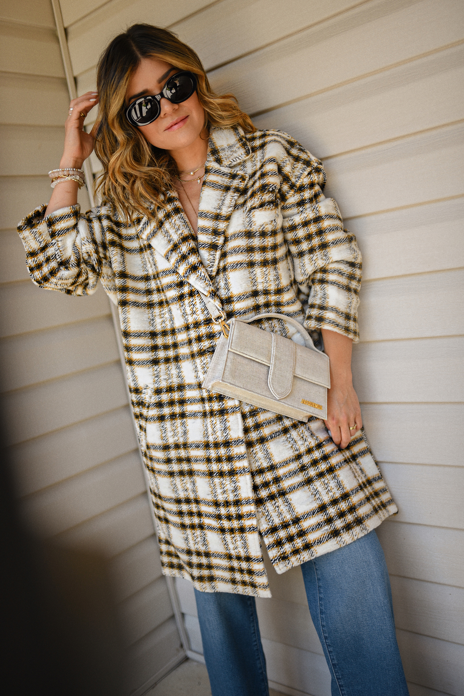 Carolina Hellal of Chic Talk wearing a Nordstrom plaid coat, Madewell wide leg jeans, Celine sunglasses, and Jacquemus Le grand Bambino Bag.