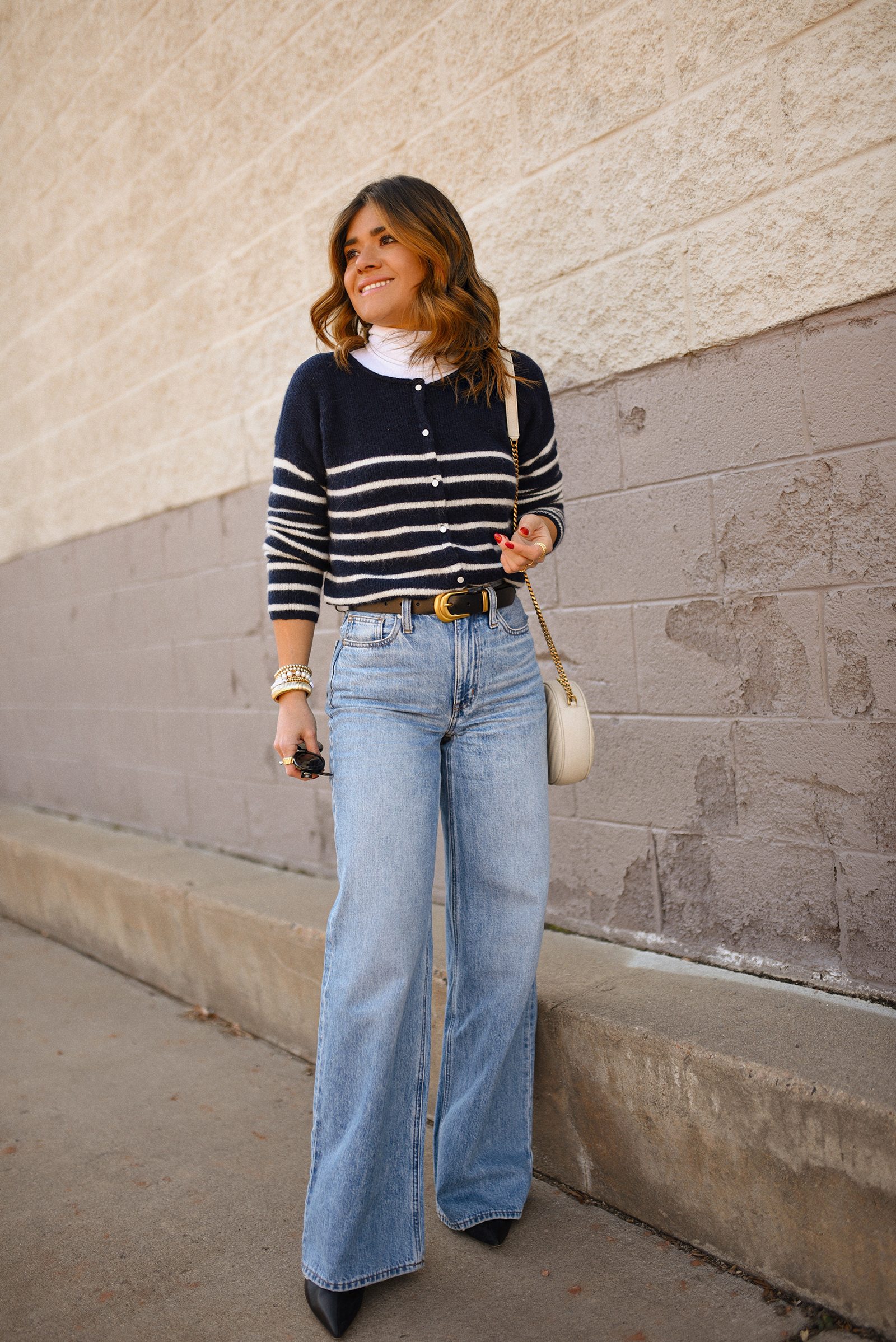 Carolina Hellal of Chic Talk wearing a Stripped cardigan from Sèzane, Madewell wide leg jeans and Yves Saint Laurent crossbody round camera bag