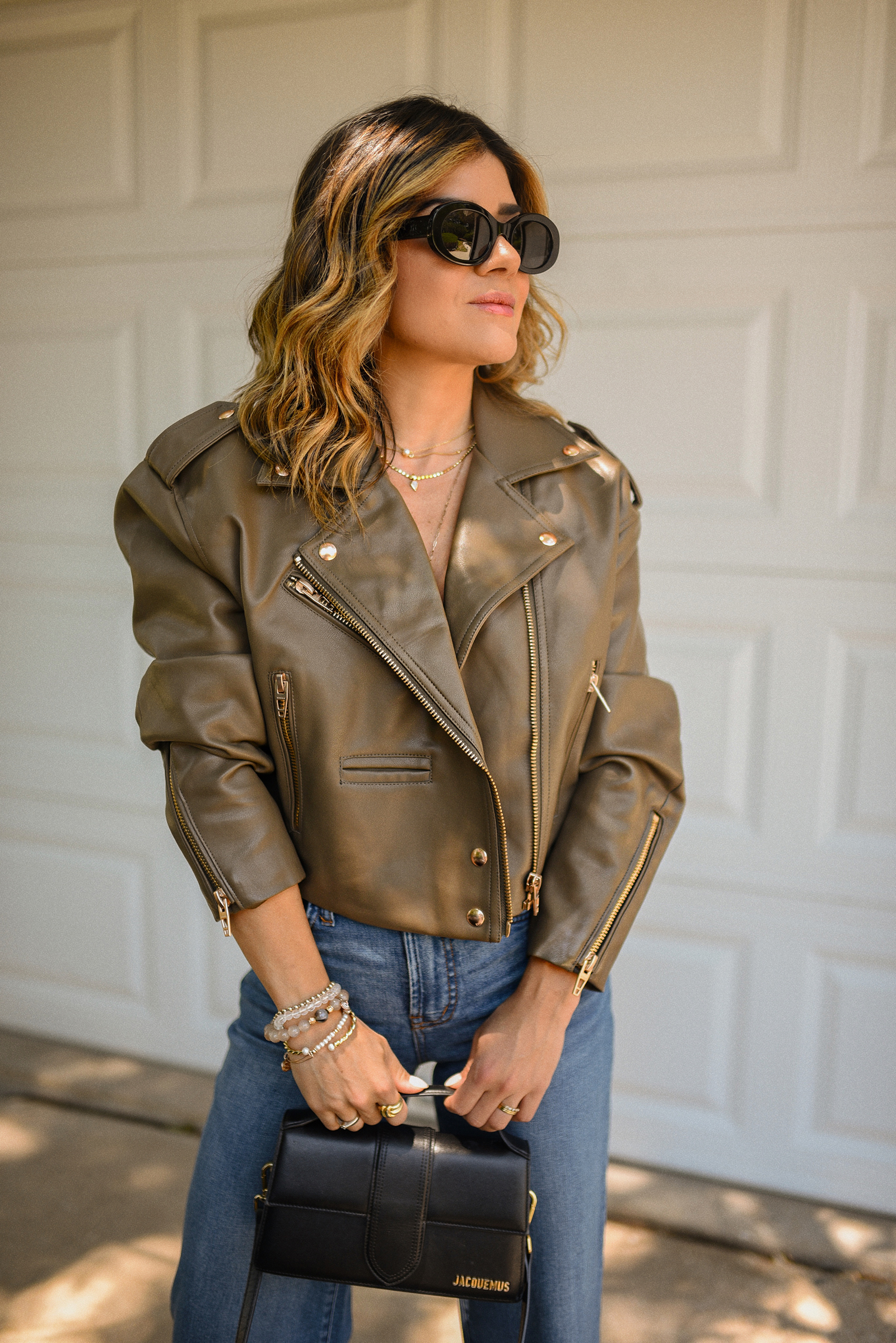 Carolina Hellal of Chic Talk wearing a wide leg jeans via Madewell, a Faux Leather Crop Moto Jacket via Nordstrom, a Nano Croc-Embossed Leather Tote via Strathberry and Celine sunglasses