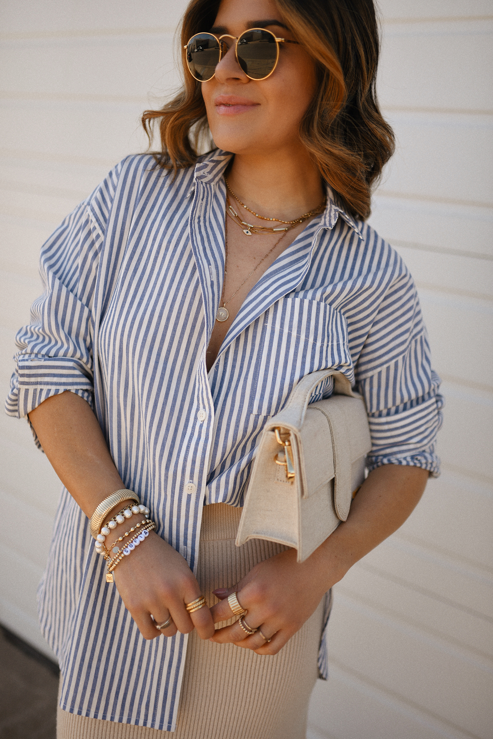Carolina Hellal of Chic Talk wearing a Madewell striped oversize shirt, a Sezane beige skirt, black sandals and Le grand Bambino bag from Jacquemus