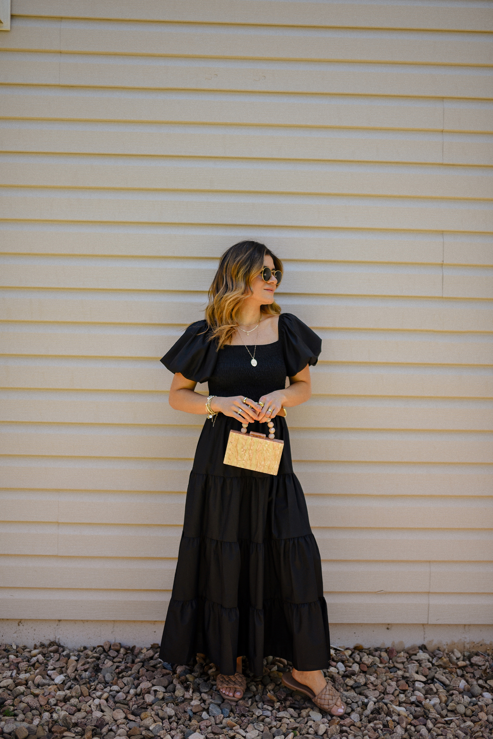 Carolina Hellal of Chic Talk wearing a blak maxi dress via Amazon, braided brown sandals, box hand bag and Ray-Ban sunglasses