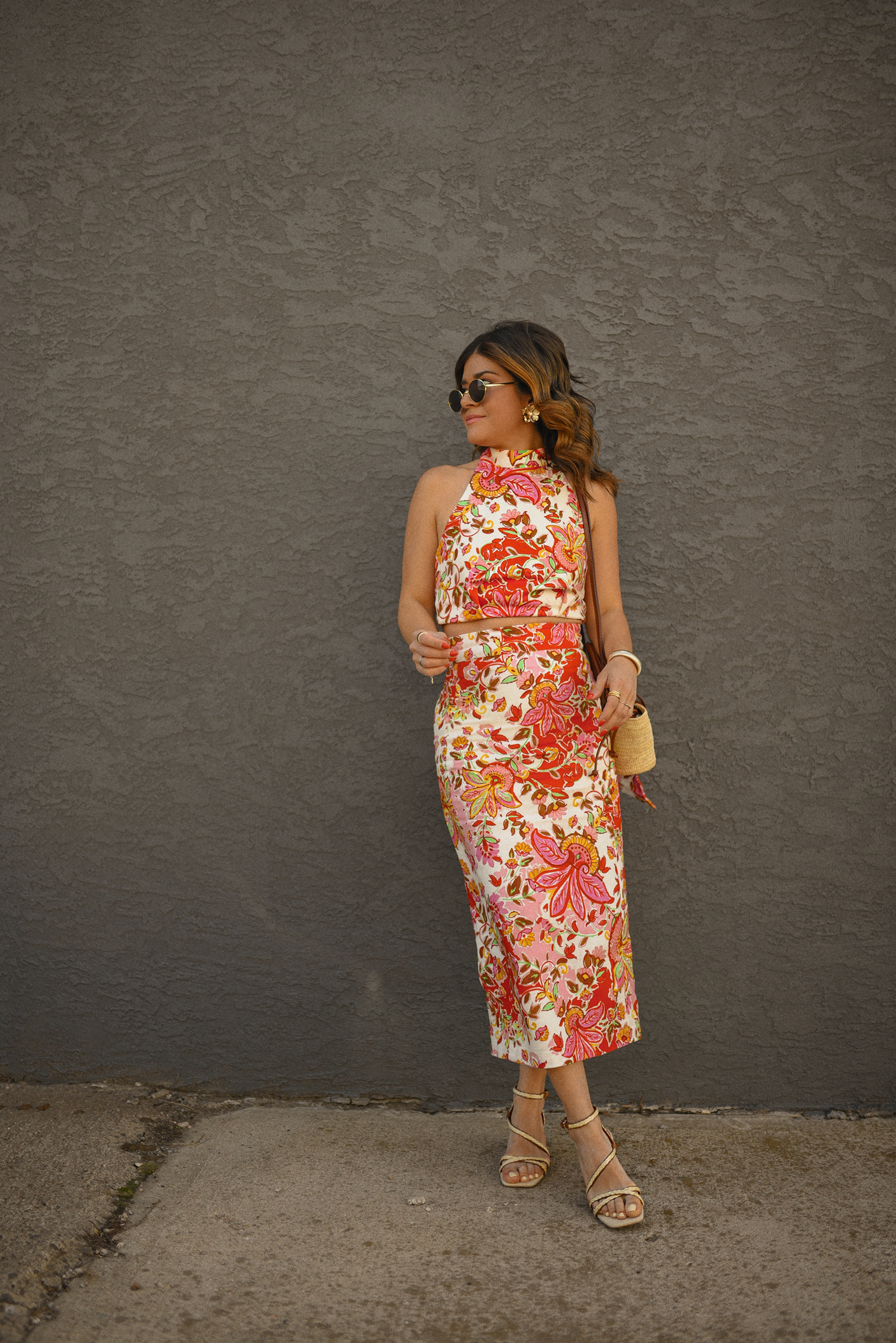 Carolina Hellal of Chic Talk wearing a Sezane floral set of top and midi skirt, a rafia bag, a Target sandals and Amazon sunglasses