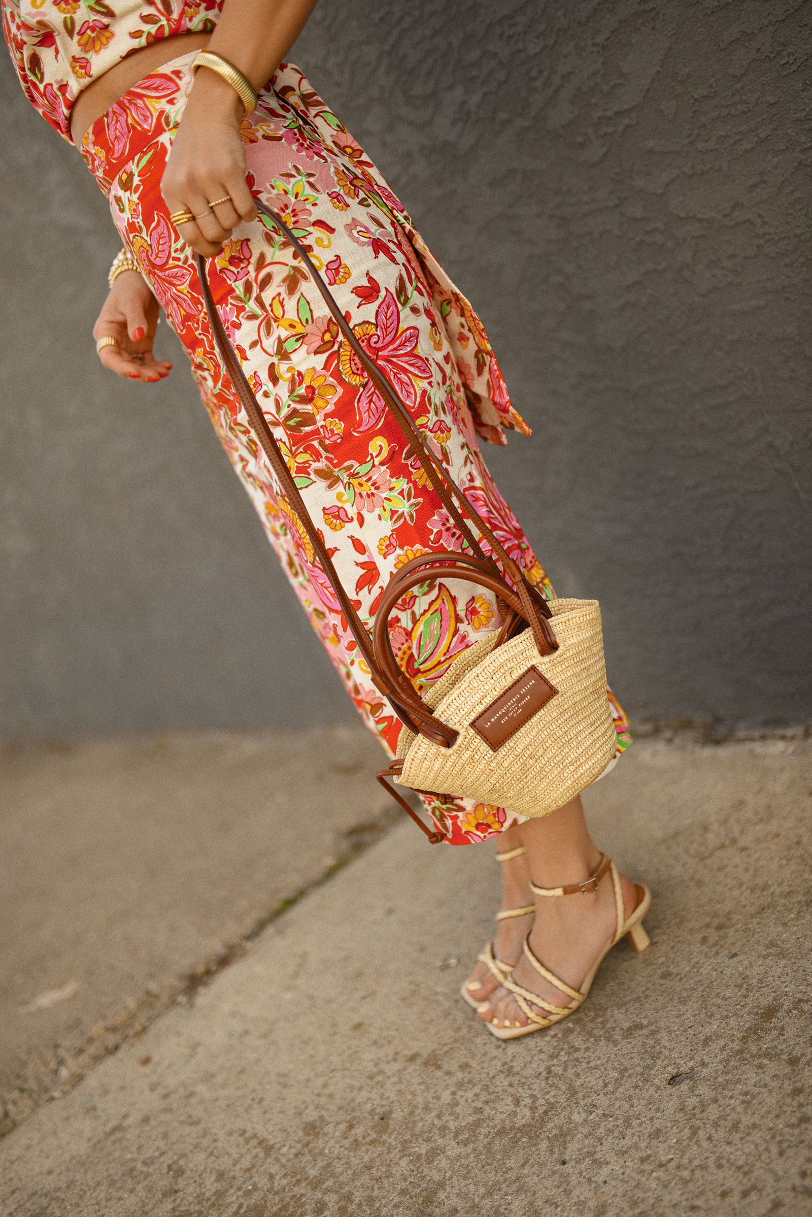 Carolina Hellal of Chic Talk wearing a Sezane floral set of top and midi skirt, a rafia bag, a Target sandals and Amazon sunglasses