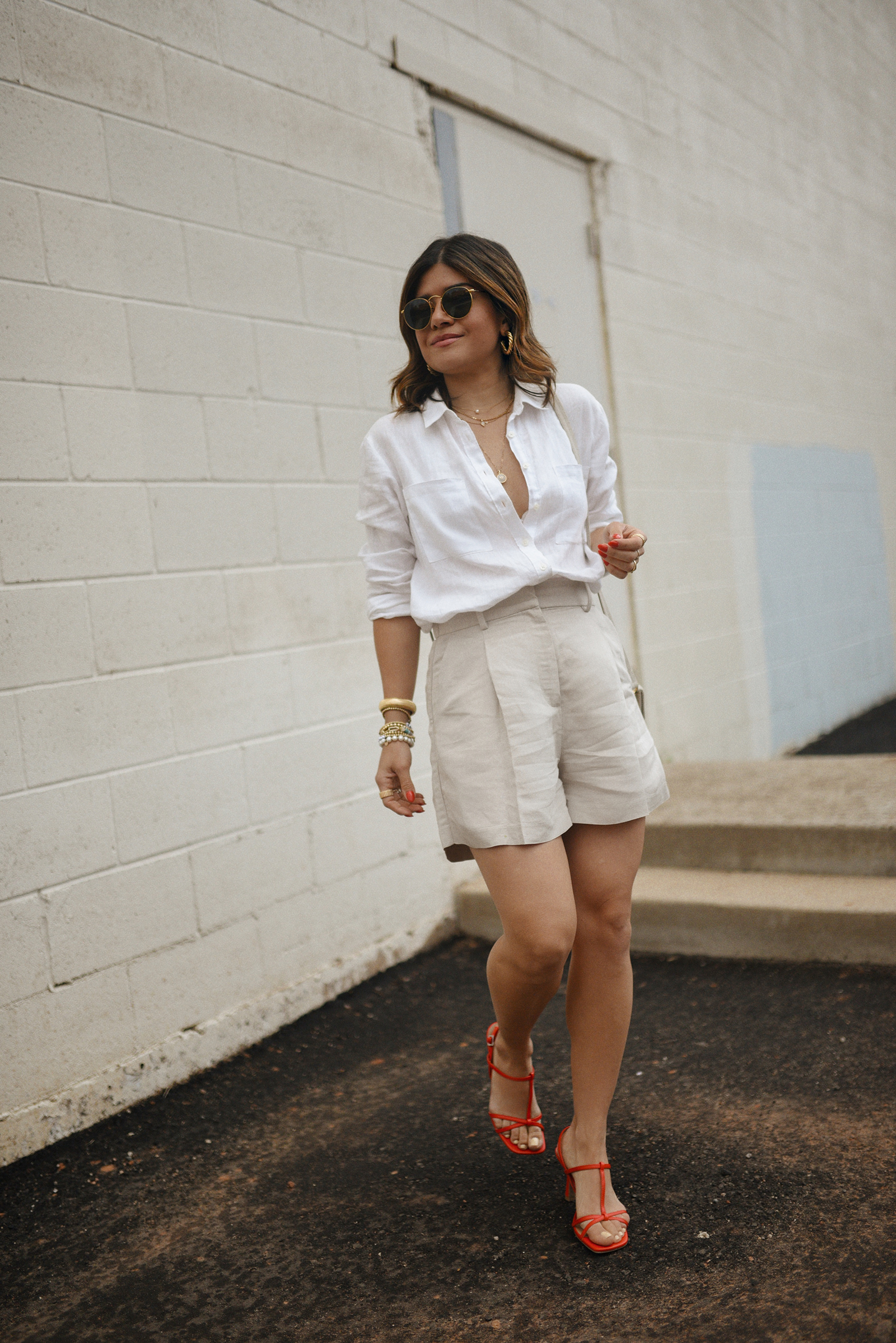 Carolina Hellal of Chic Talk wearing a linen shirt via BODEN, linen shorts from H&M, red sandals via Target, Rayban sunglasses and JAcquemus bag