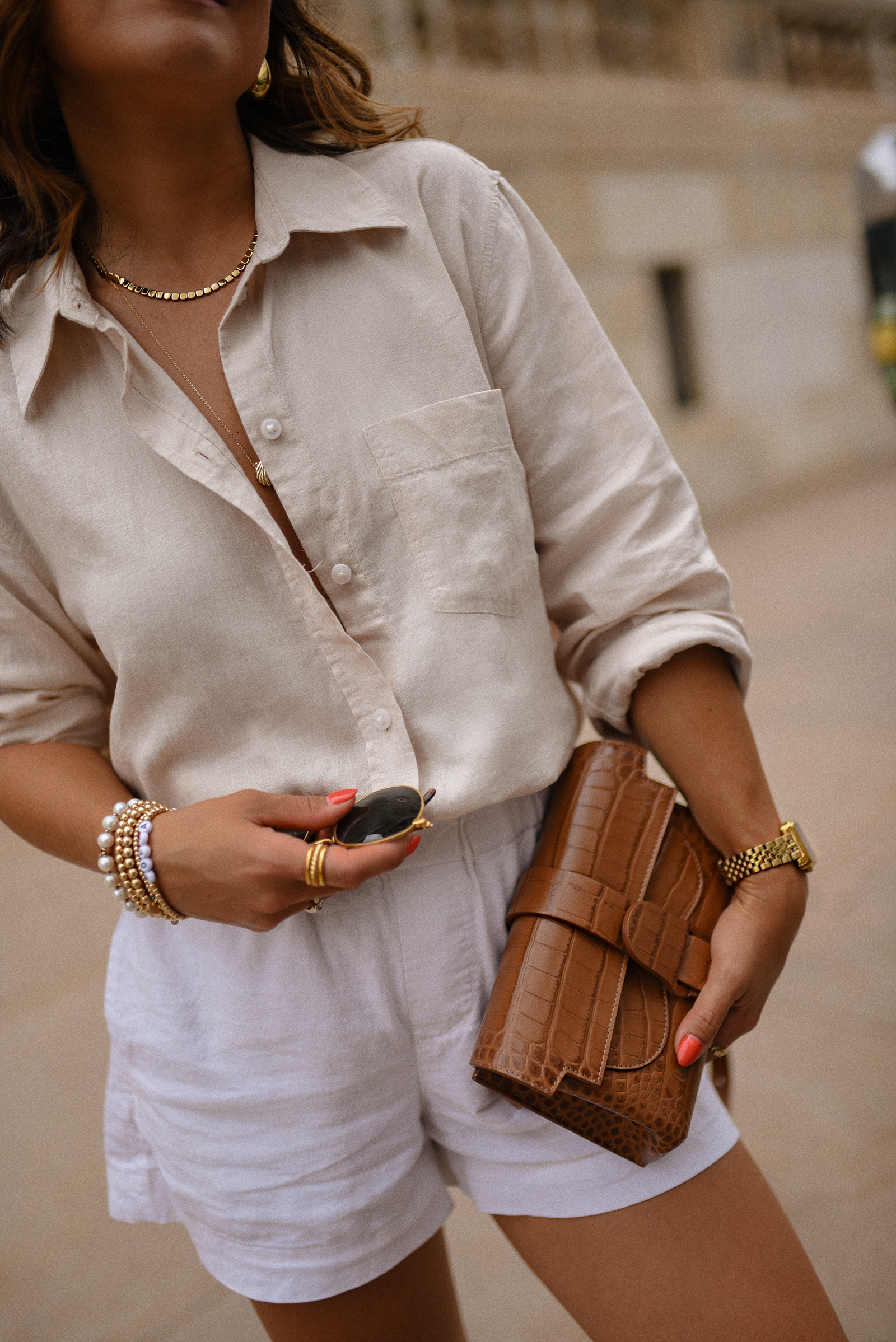 Carolina Hellal of Chic Talk wearing a white shorts via Target, H&M linen shirt, Sezane sandals and Senreve Aria handbag