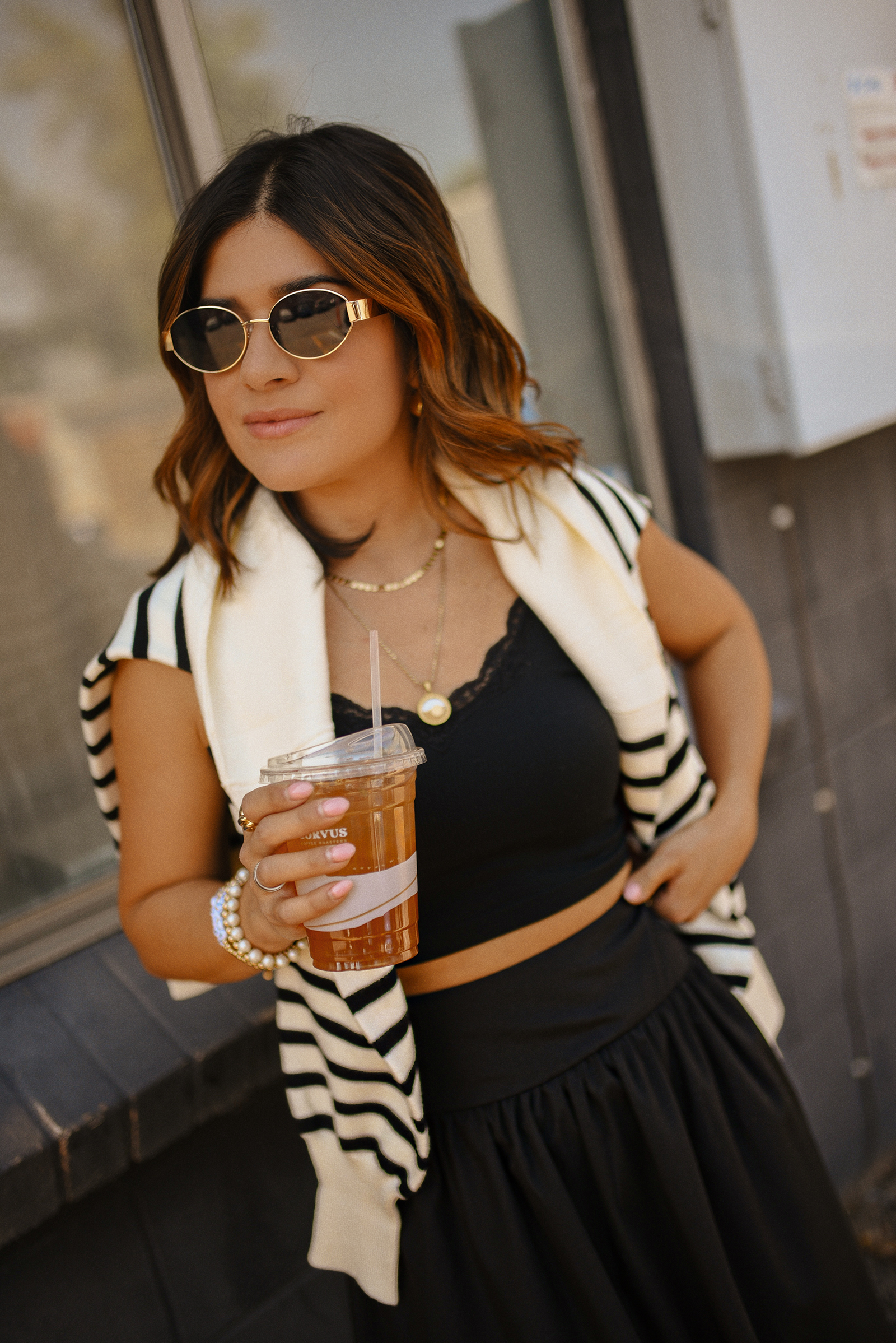 Carolina Hellal of Chic Talk wearing a bubble hem maxi skirt, a stripped sweater, a mesh Mary Jane flats and sunglasses via Amazon, a black crop top from Target and red handbag via Anthropologie