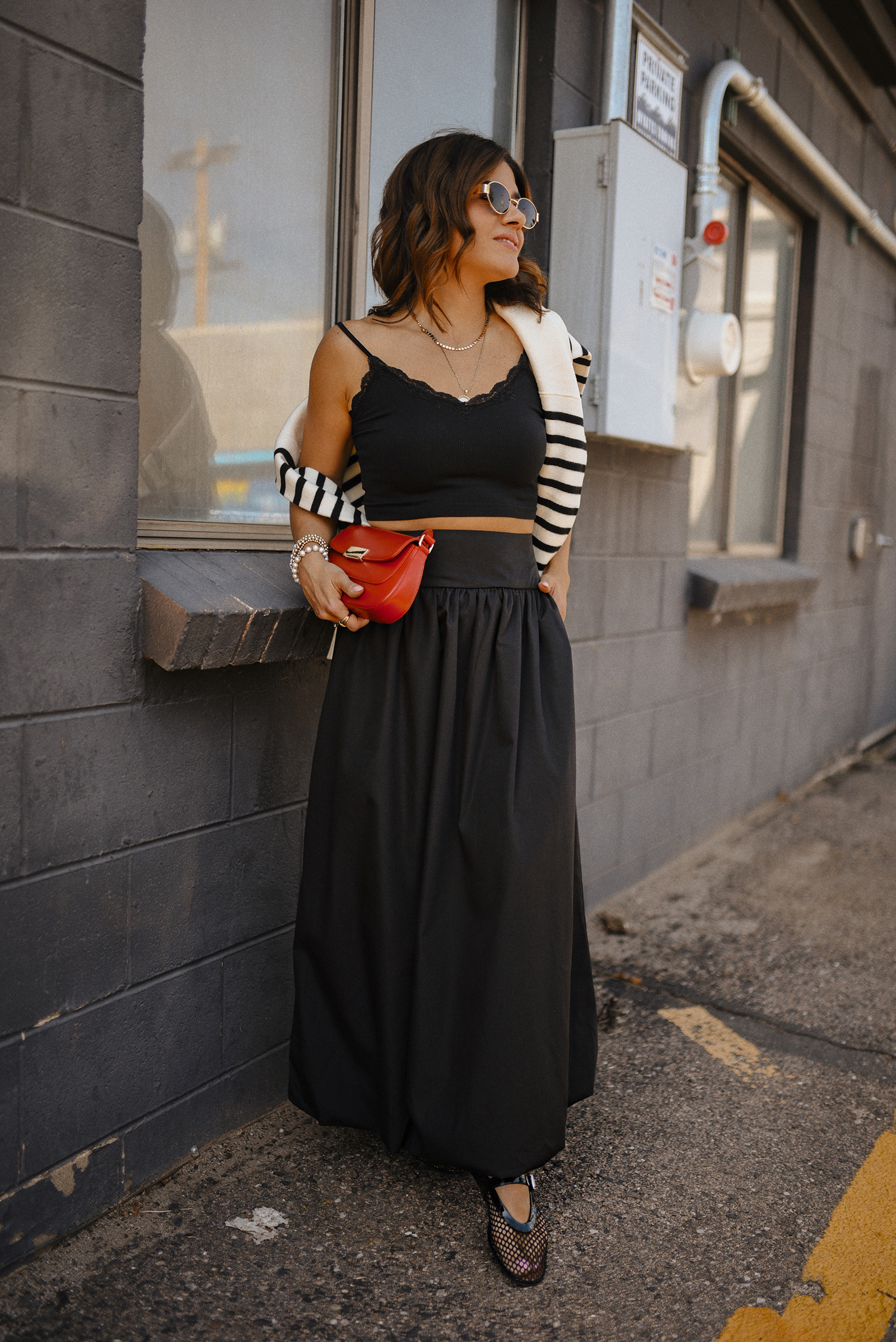 Carolina Hellal of Chic Talk wearing a bubble hem maxi skirt, a stripped sweater, a mesh Mary Jane flats and sunglasses via Amazon, a black crop top from Target and red handbag via Anthropologie