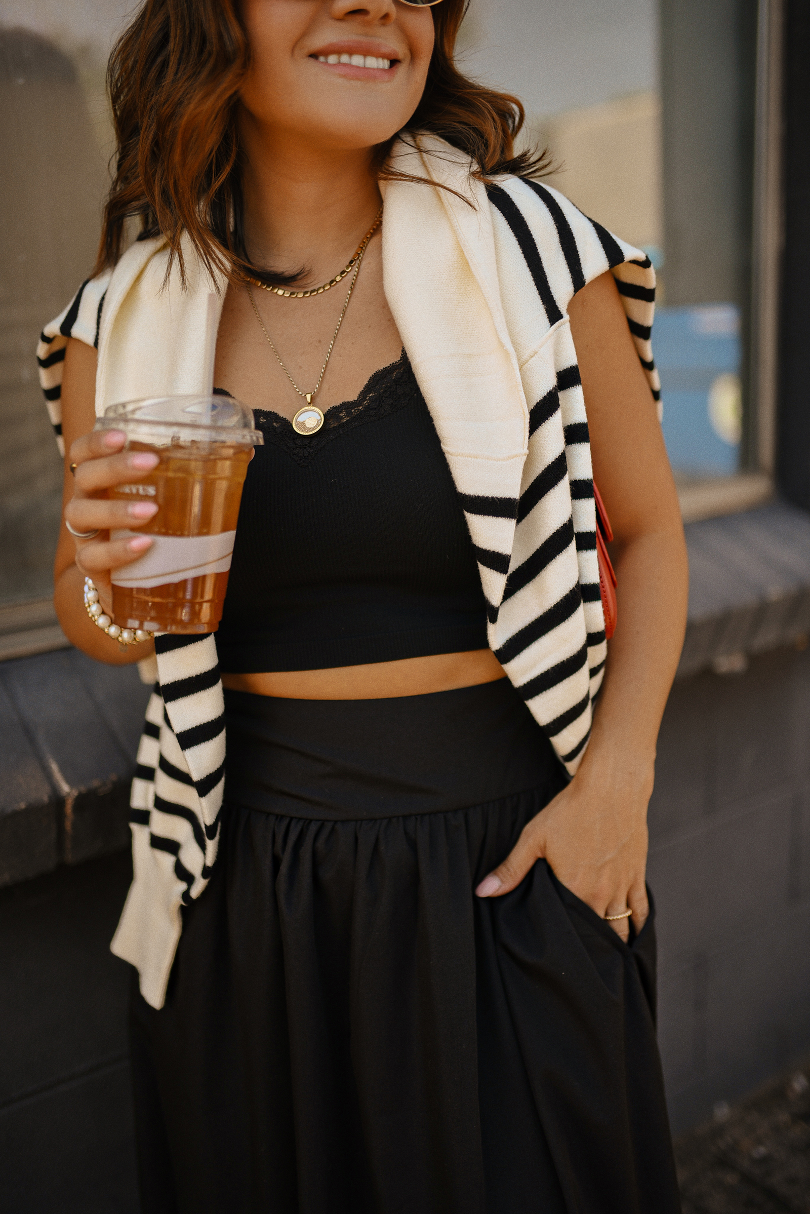 Carolina Hellal of Chic Talk wearing a bubble hem maxi skirt, a stripped sweater, a mesh Mary Jane flats and sunglasses via Amazon, a black crop top from Target and red handbag via Anthropologie